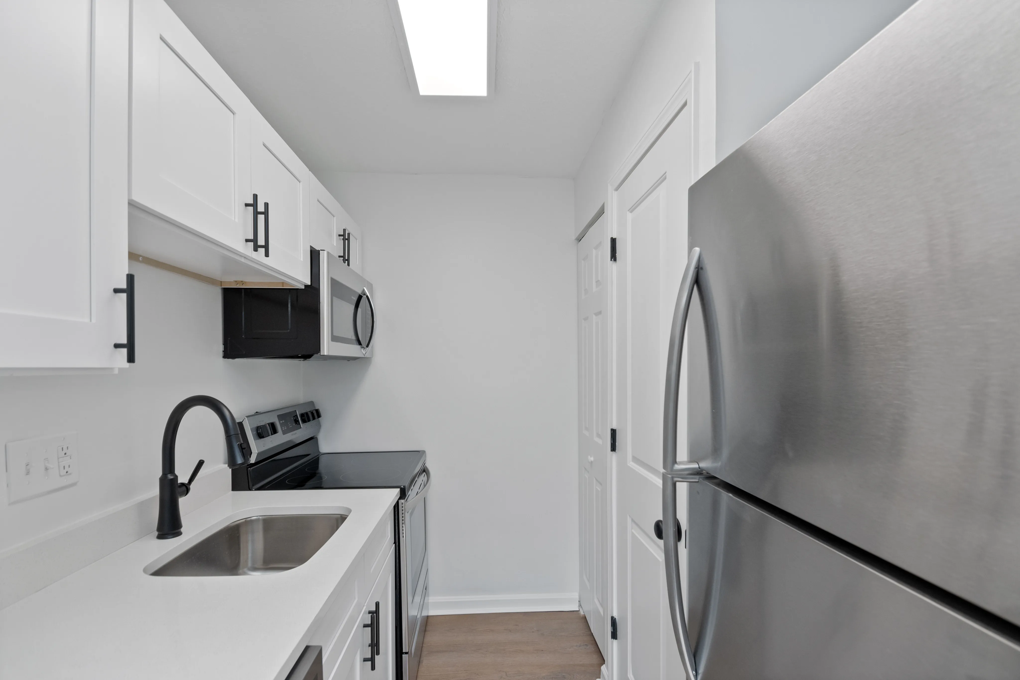 Contemporary kitchen with stainless steel appliances and white cabinetry.