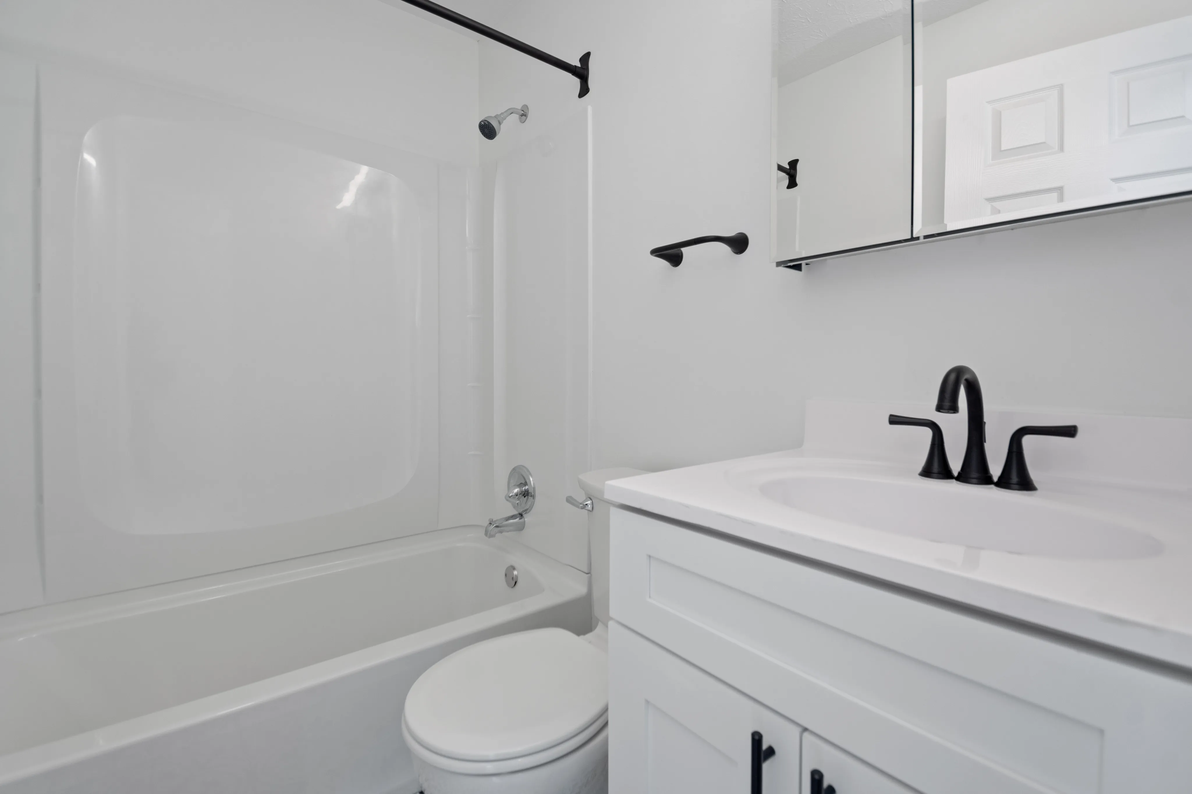 Sleek, modern bathroom with a white bathtub, sink, and black faucet accents.