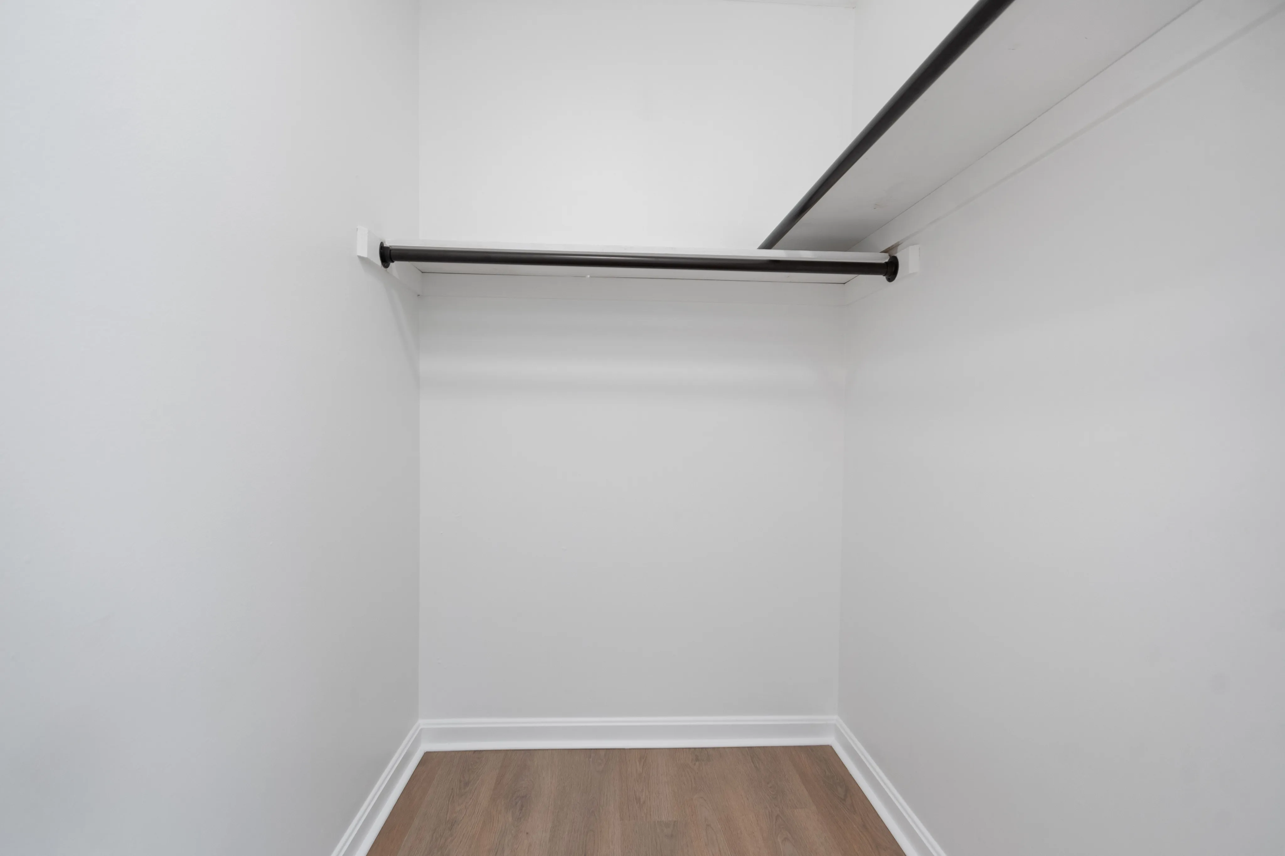 Bright and welcoming walk-in closet with ample hanging space and hardwood floors.