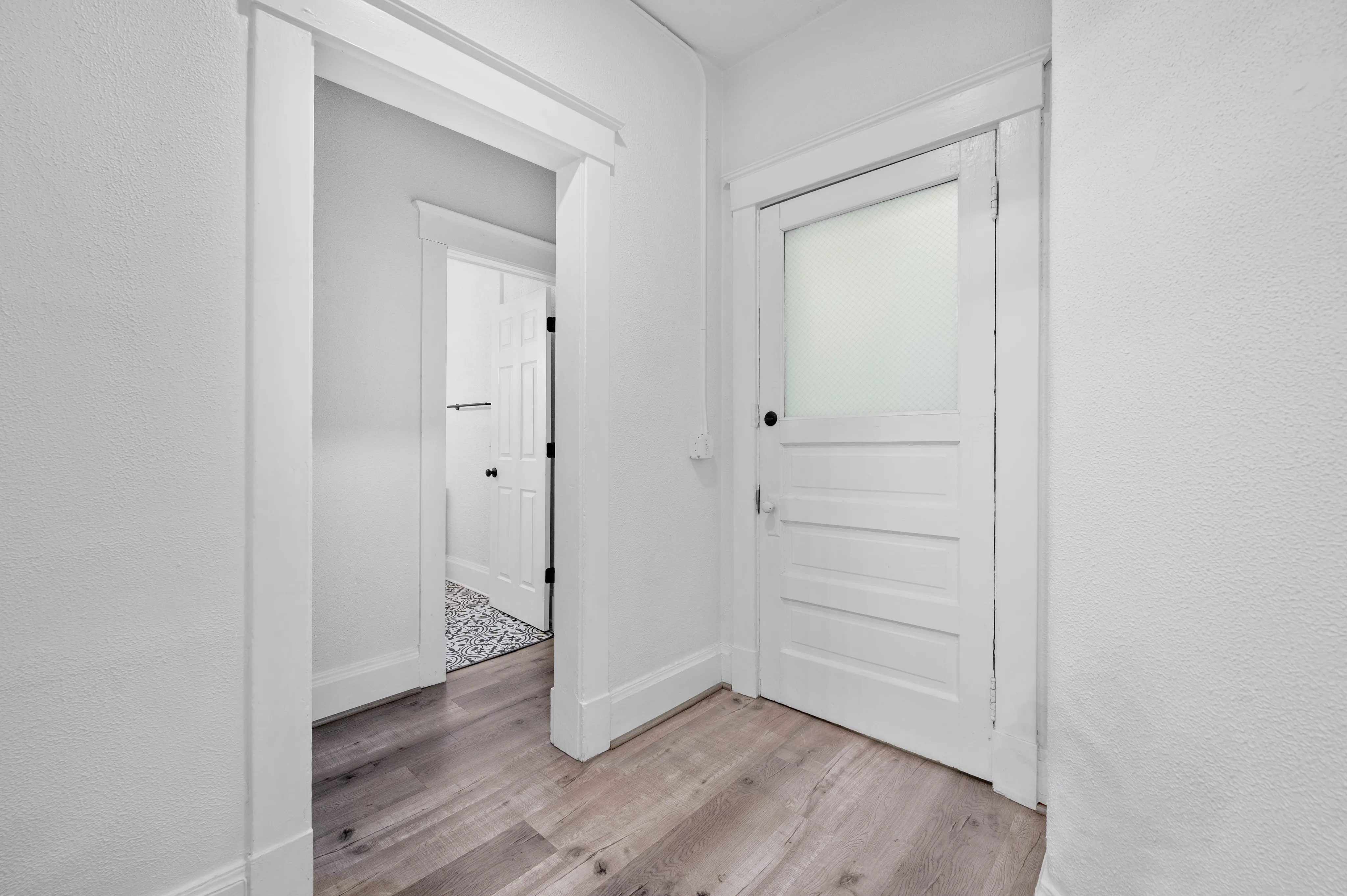 Bright hallway with modern wooden flooring and classic white doors, offering a welcoming entrance to a stylish apartment.