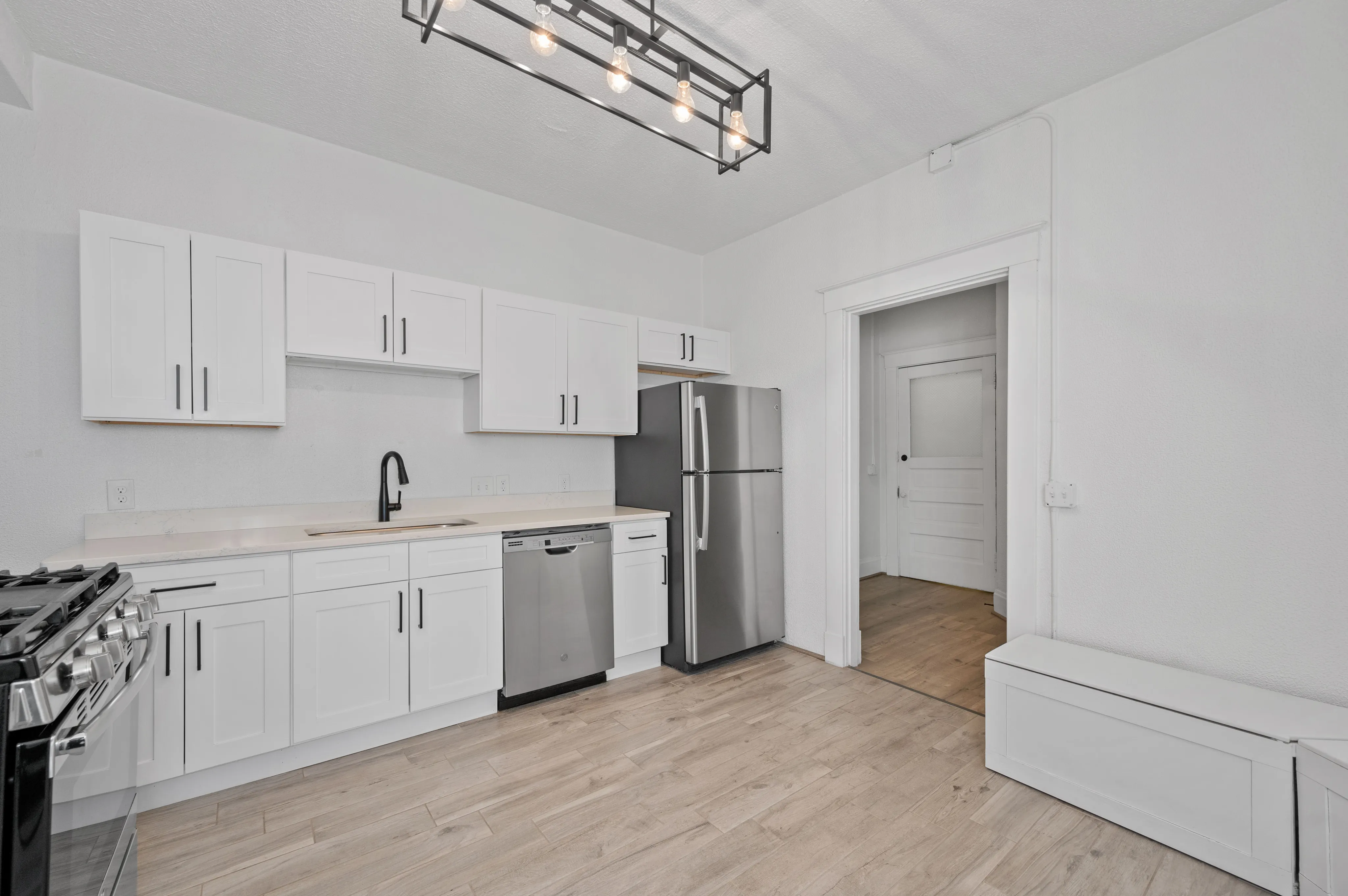 Bright modern kitchen with sleek stainless steel appliances, elegant white cabinetry, and chic pendant lighting, offering a stylish and functional cooking space.