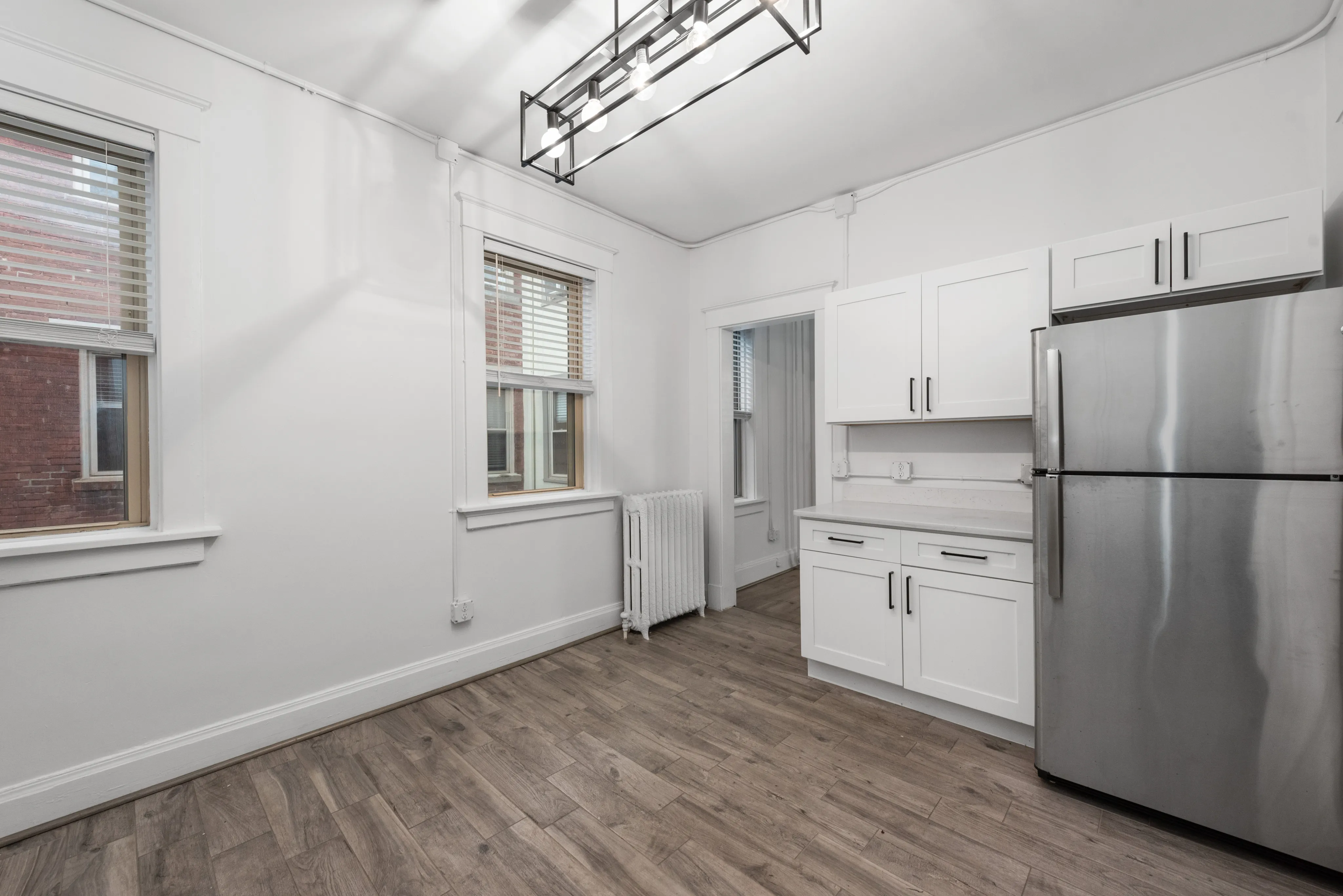 Bright and modern kitchen with sleek stainless steel appliances, elegant white cabinetry, and stylish wood flooring.