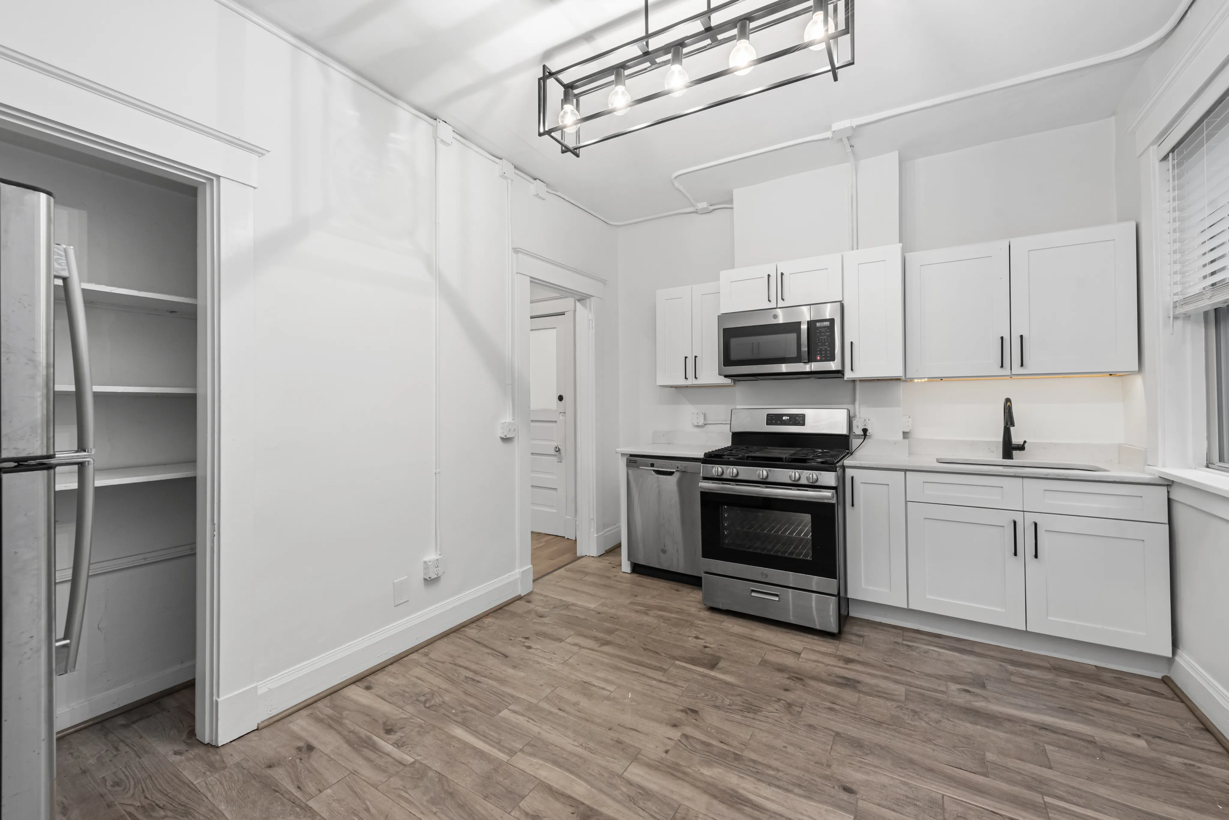 Modern kitchen with sleek white cabinetry, stainless steel appliances, and elegant wood flooring, creating a bright and welcoming space.