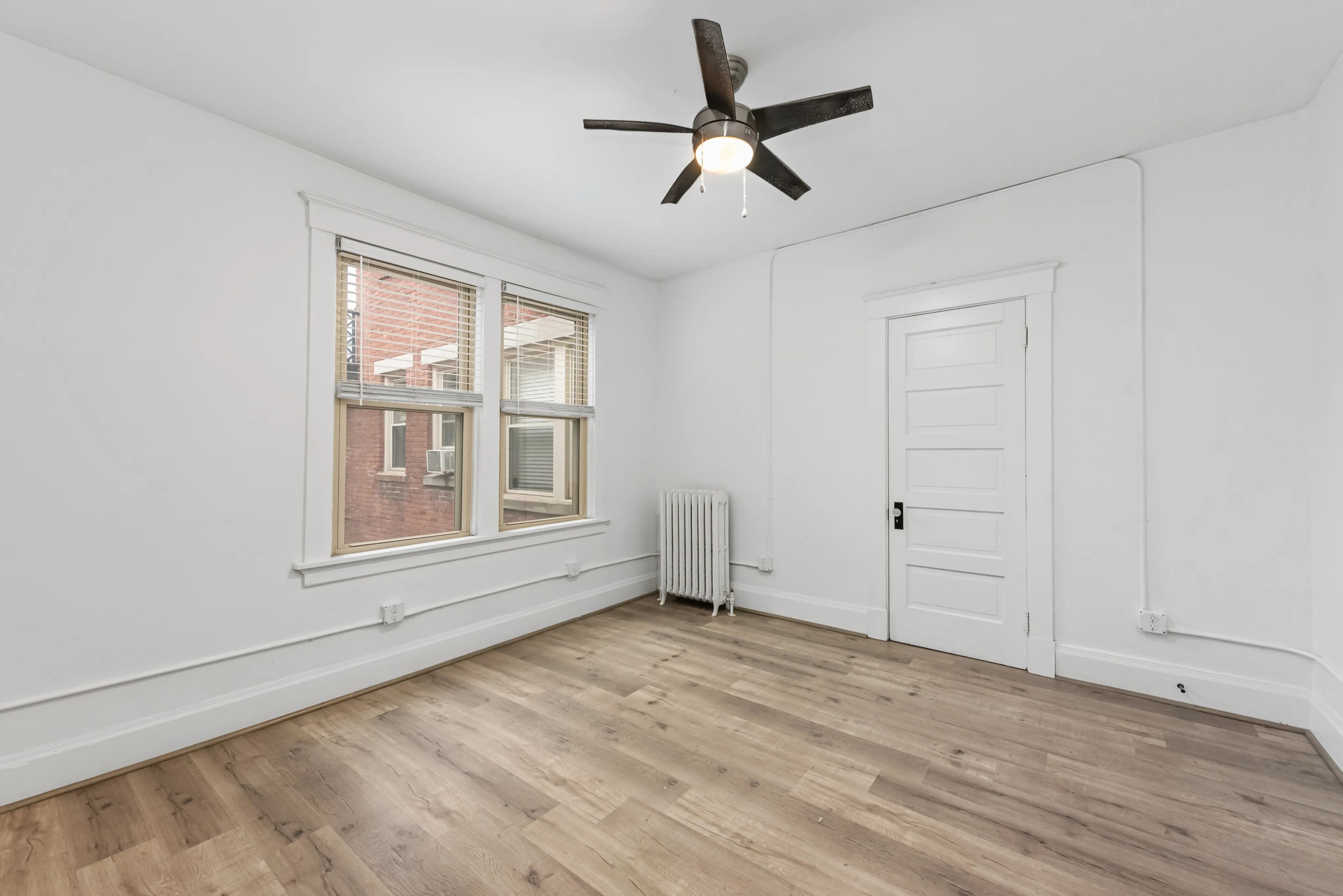 Bright and airy room featuring elegant hardwood floors, a sleek ceiling fan, and large windows offering plenty of natural light.