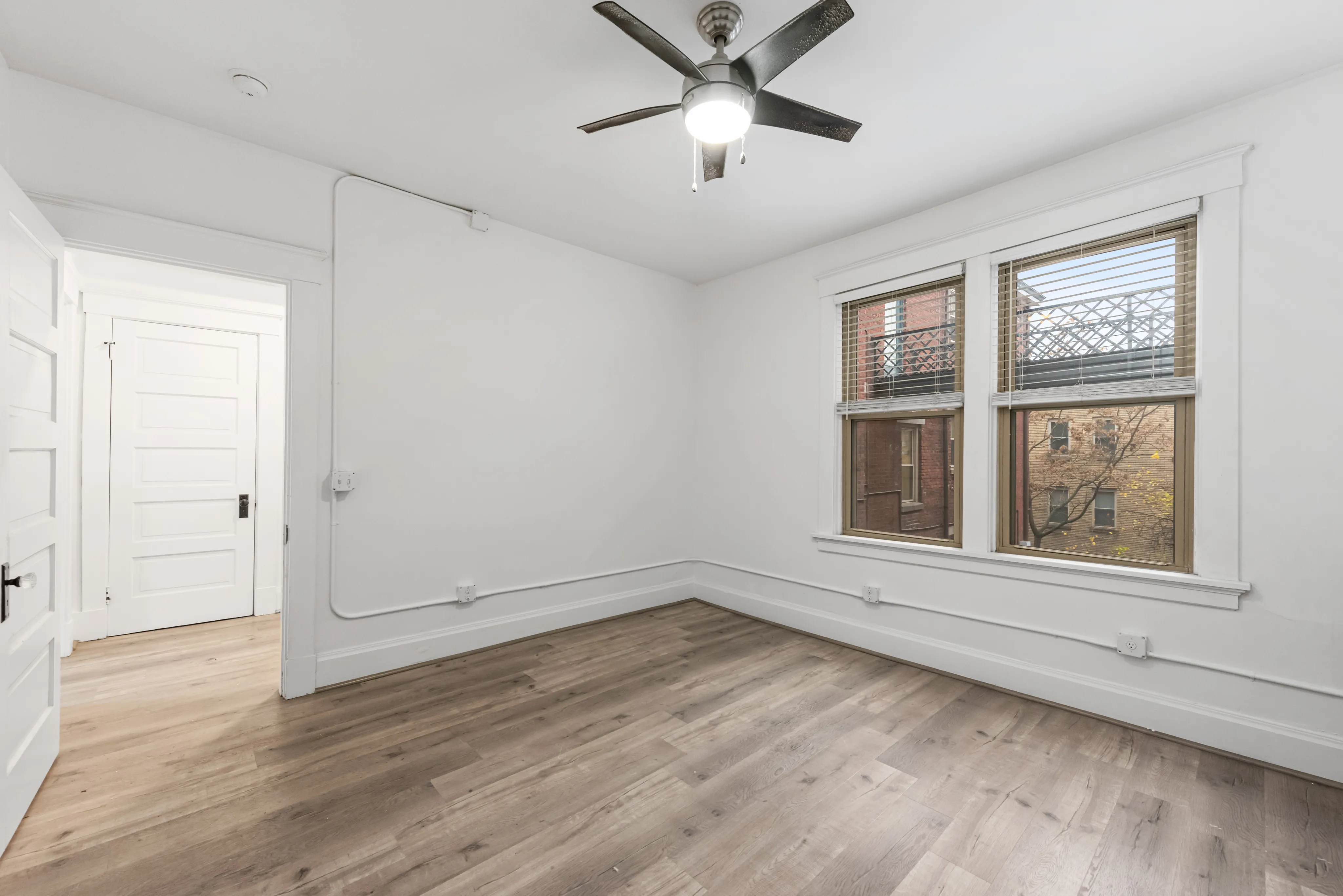 Bright and airy room featuring elegant hardwood floors, large windows with a view, and a ceiling fan for comfort.