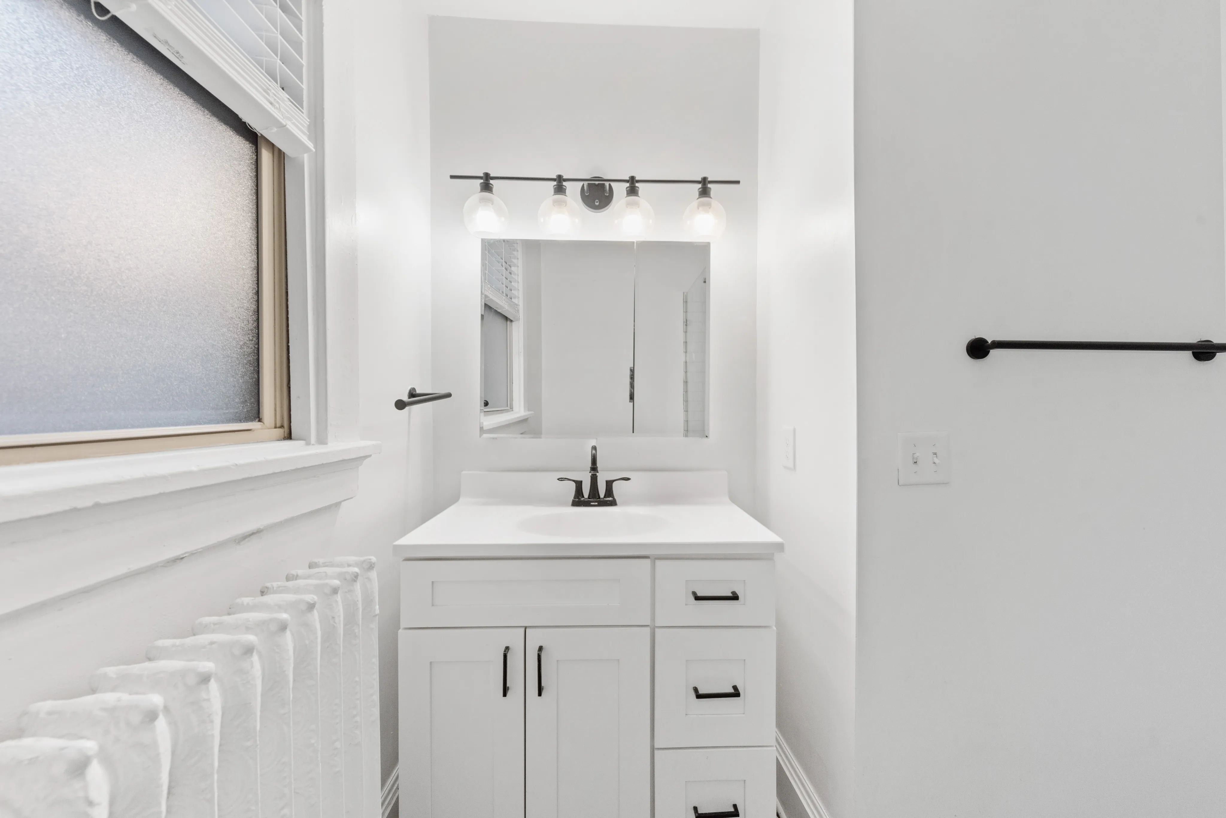 Bright, modern bathroom with sleek white vanity, stylish lighting, and a large mirror, perfect for a refreshing start to the day.