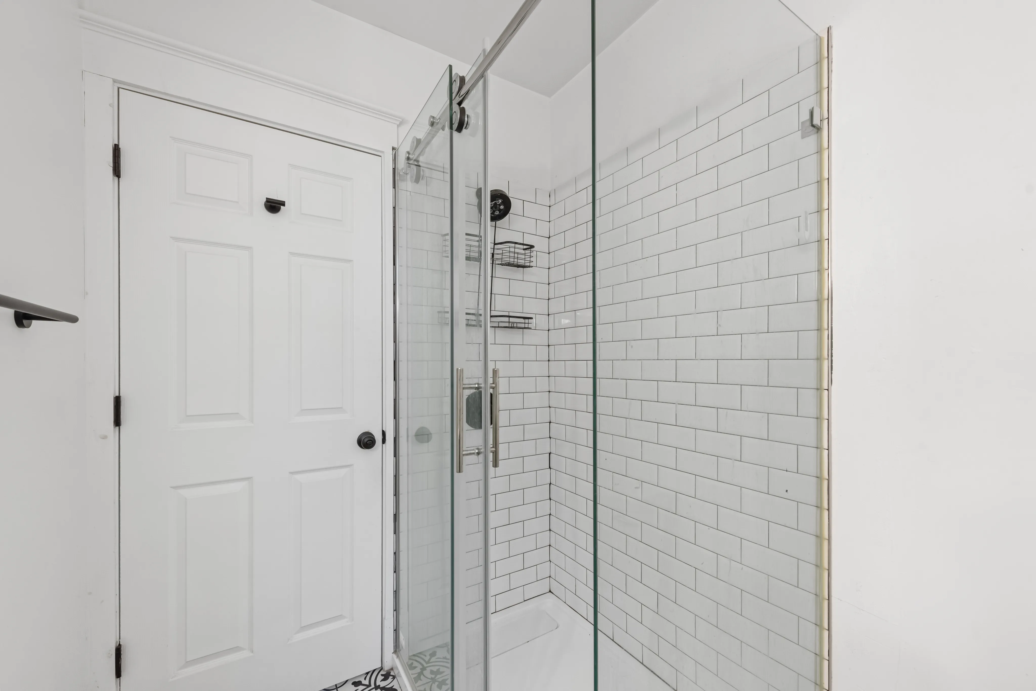 Modern bathroom featuring a sleek glass shower with classic subway tiles and stylish black hardware.