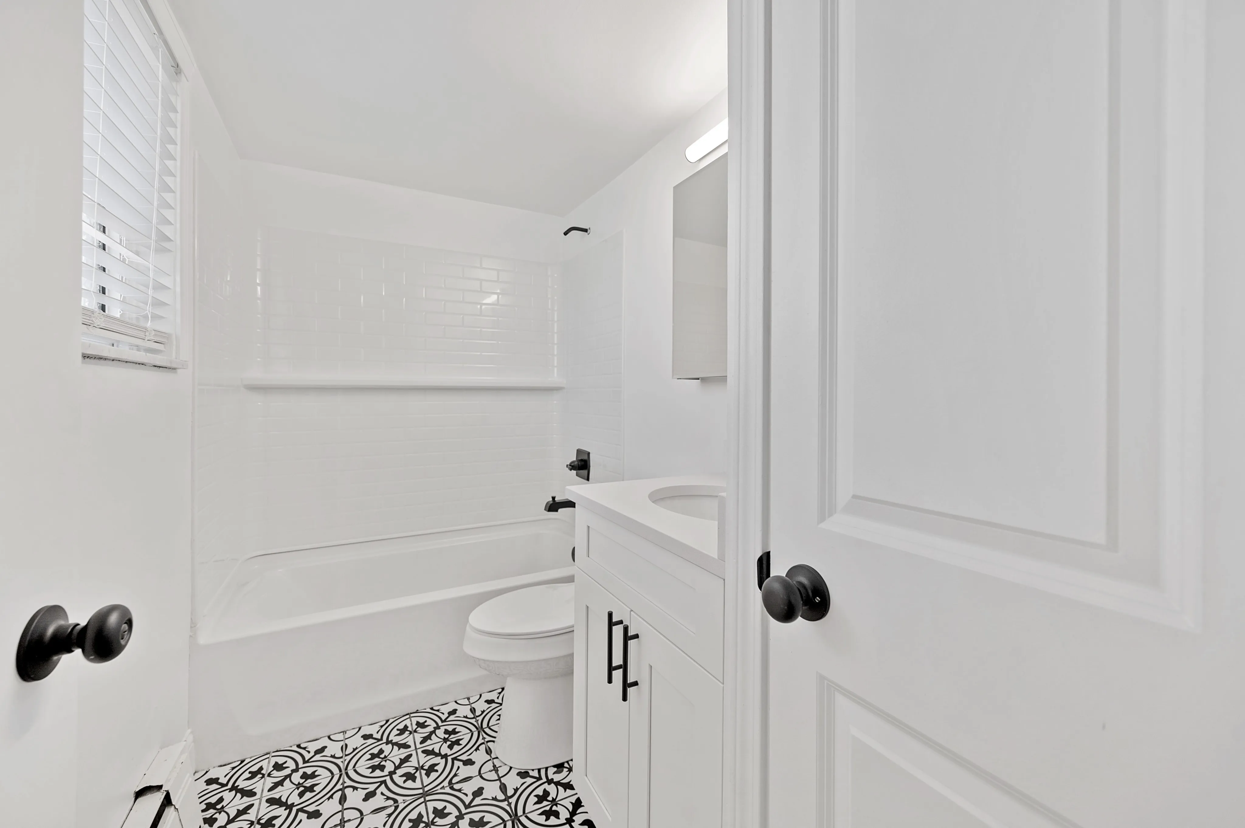 Elegant bathroom featuring crisp white tiles, a modern sink, and stylish patterned flooring.