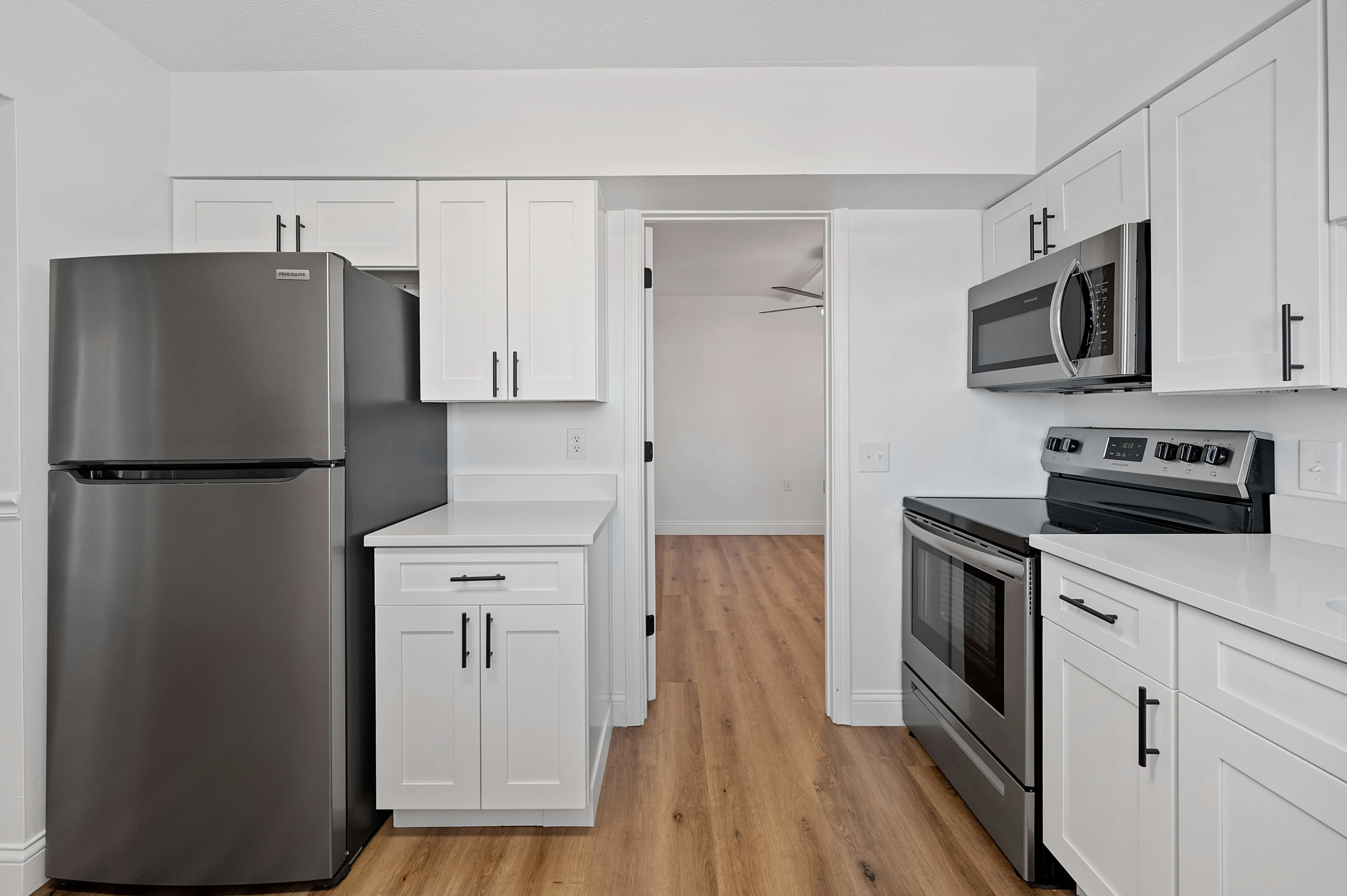 Modern kitchen with sleek stainless steel appliances, white cabinetry, and elegant hardwood flooring.