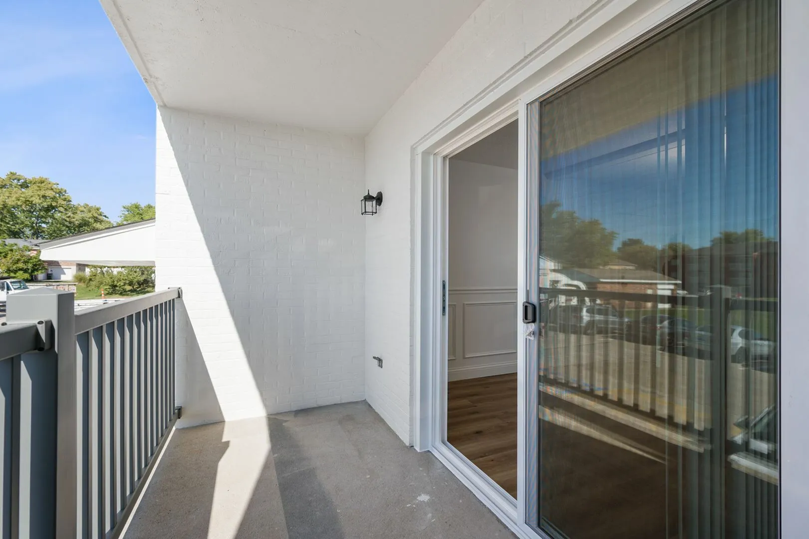 Bright and airy balcony with sleek railing and sliding glass doors, perfect for relaxing outdoors.