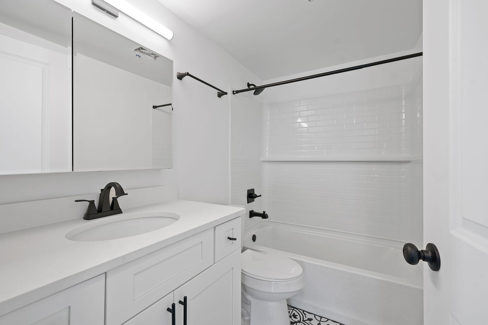 Modern bathroom featuring sleek white cabinetry, a spacious bathtub, and elegant black fixtures.