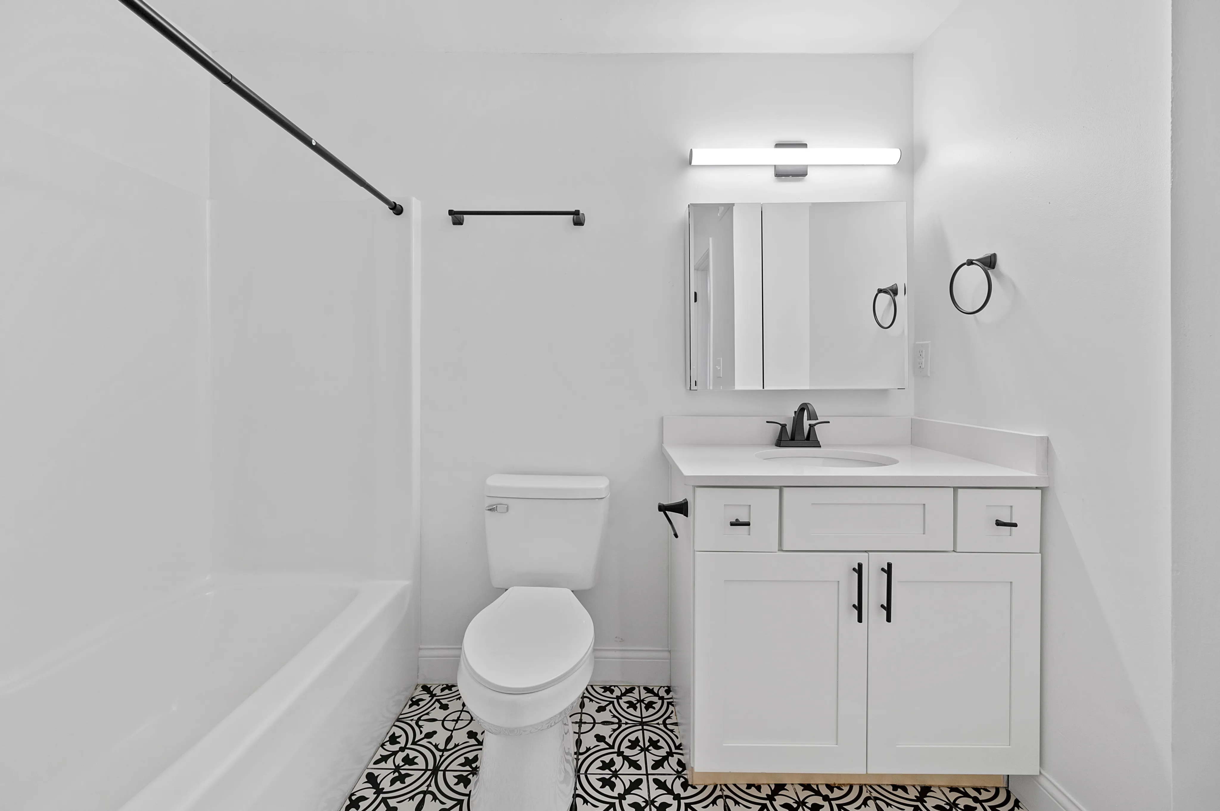 Elegant bathroom with modern fixtures, pristine white walls, and stylish patterned floor tiles.