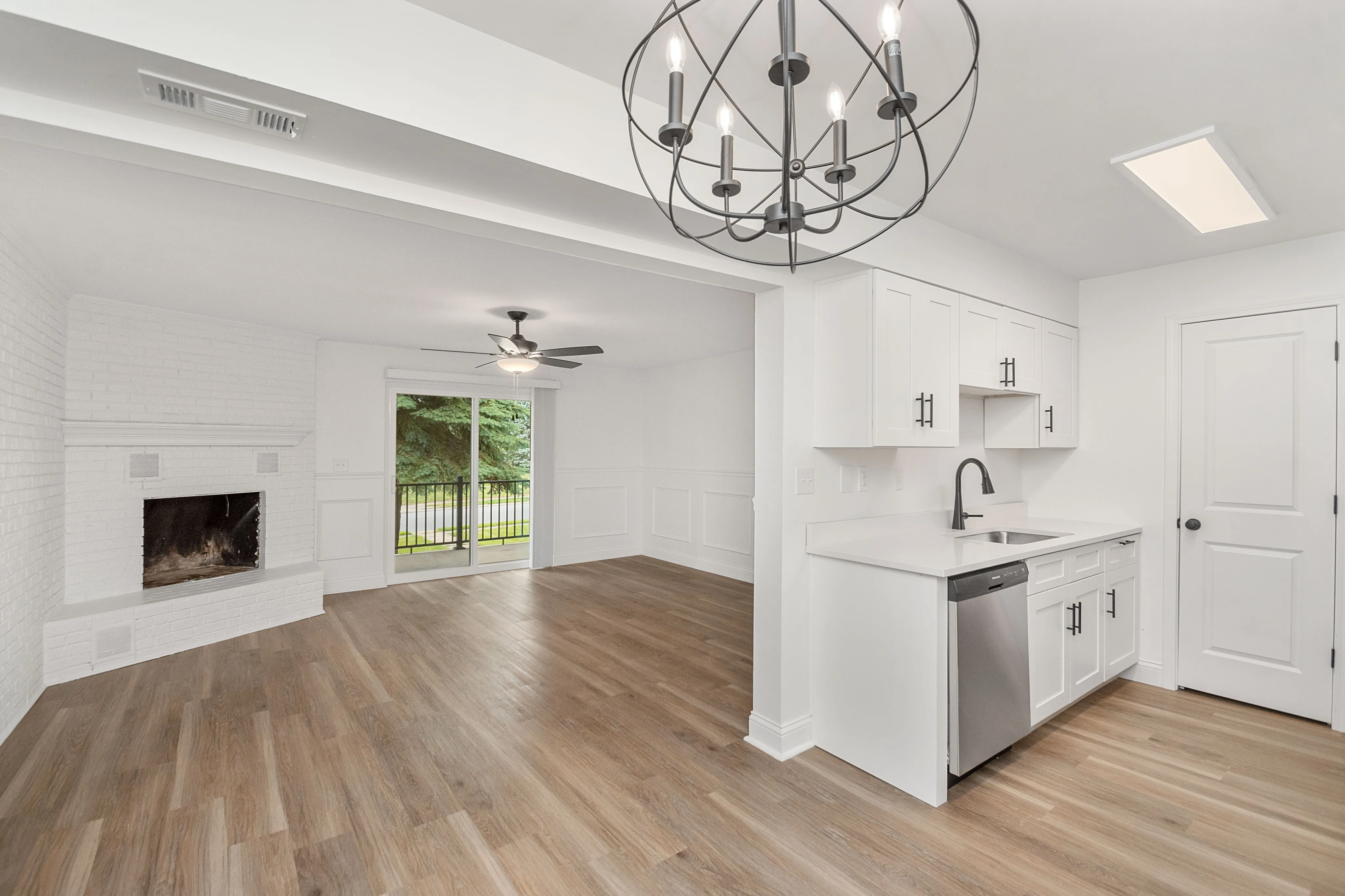 Elegant open-concept apartment featuring a modern kitchen with stainless steel appliances, spacious living area with fireplace, and beautiful hardwood floors.