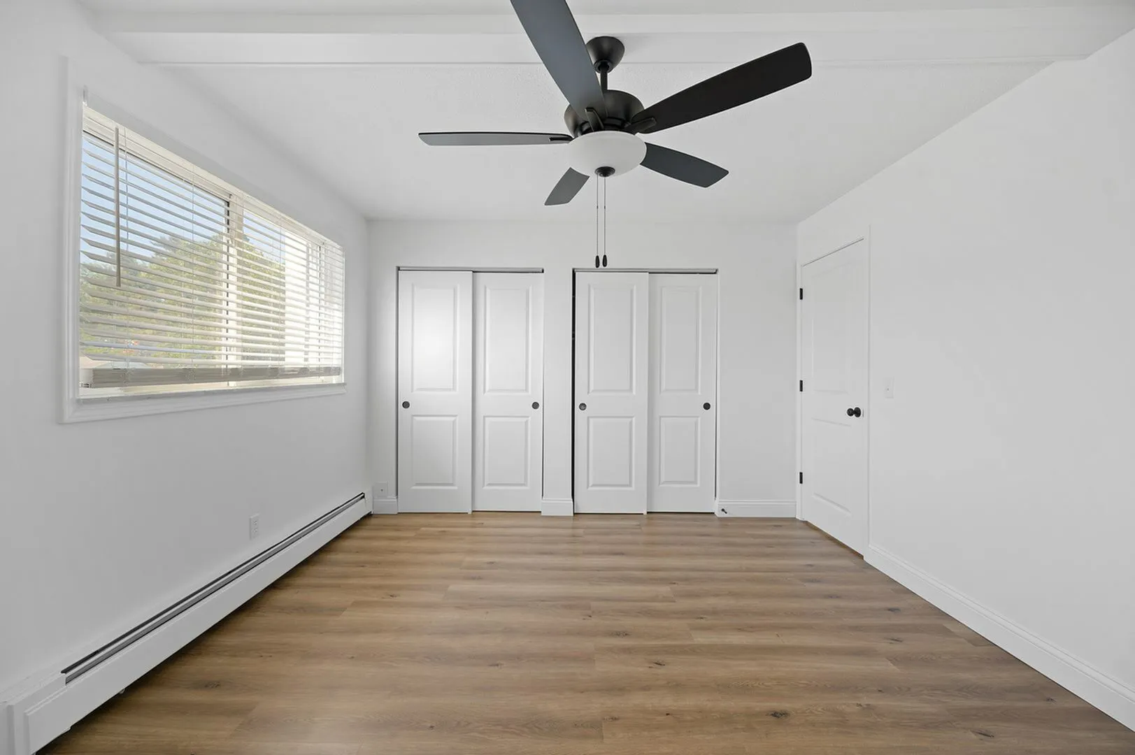 Bright, spacious bedroom with modern ceiling fan, elegant hardwood floors, and ample closet space.