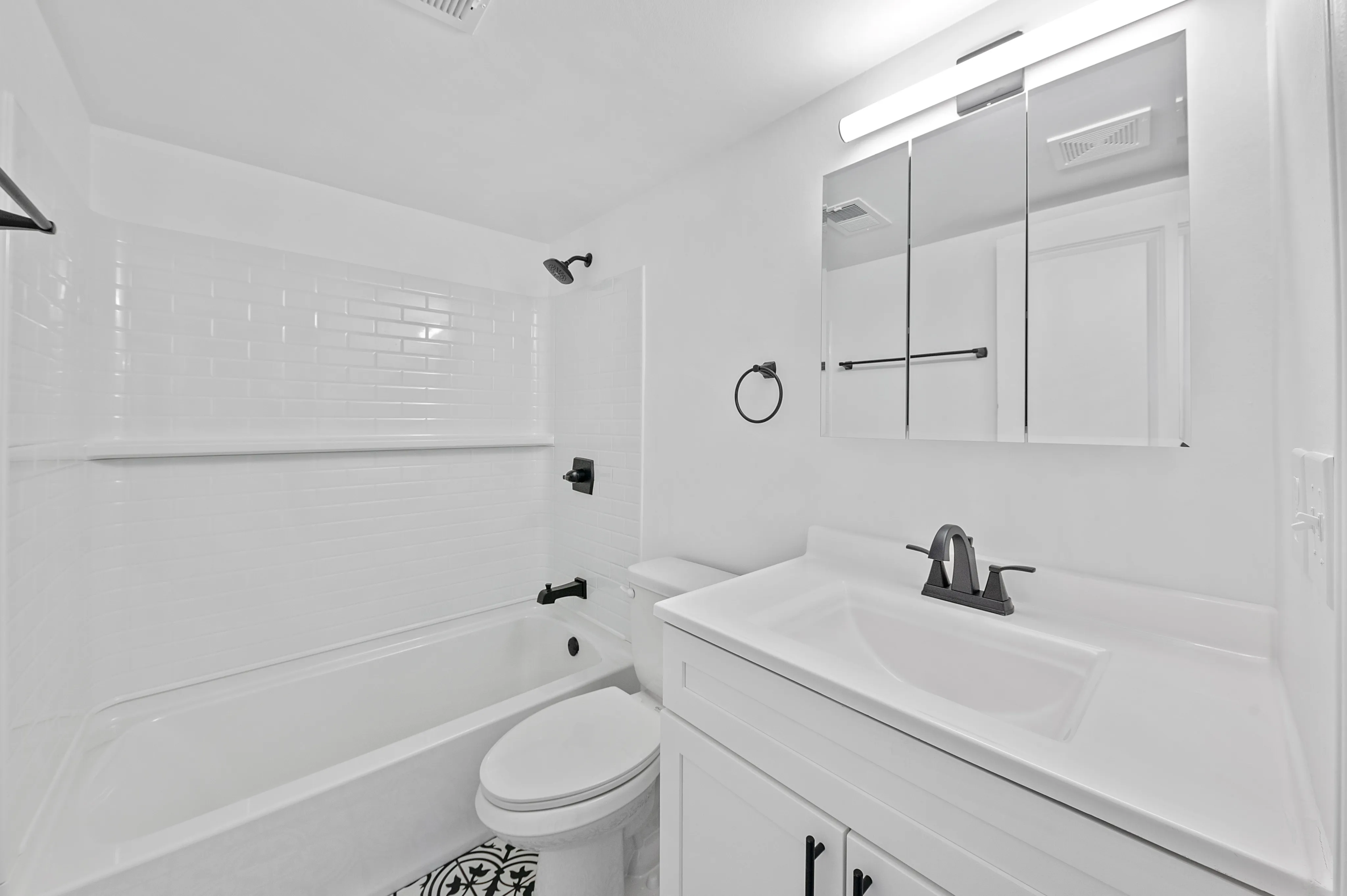 Sleek modern bathroom featuring white subway tiles, elegant black fixtures, and a spacious vanity with mirrored cabinets.