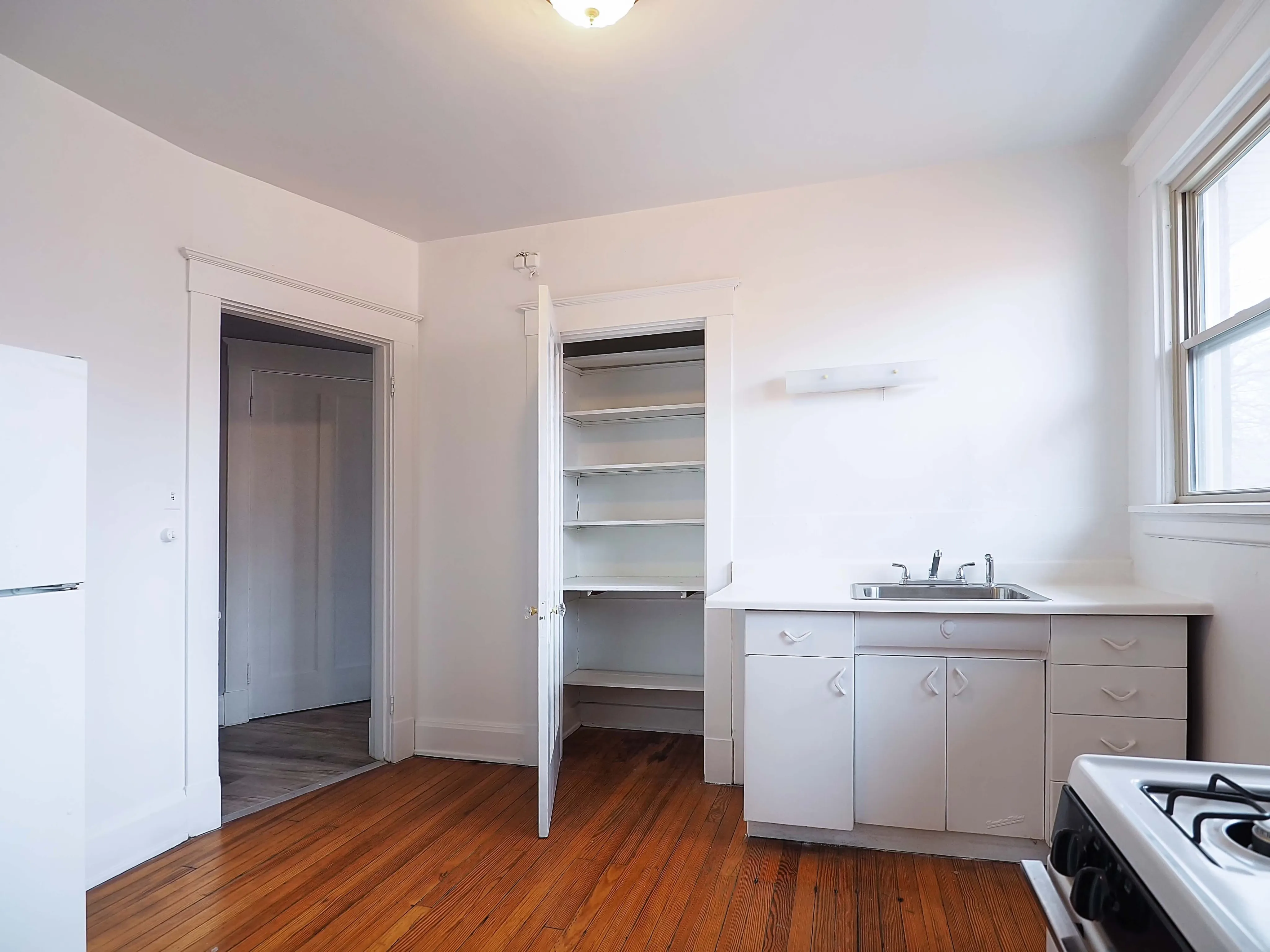 Bright kitchen with hardwood floors, ample counter space, and open shelving, ideal for home cooking and entertaining.