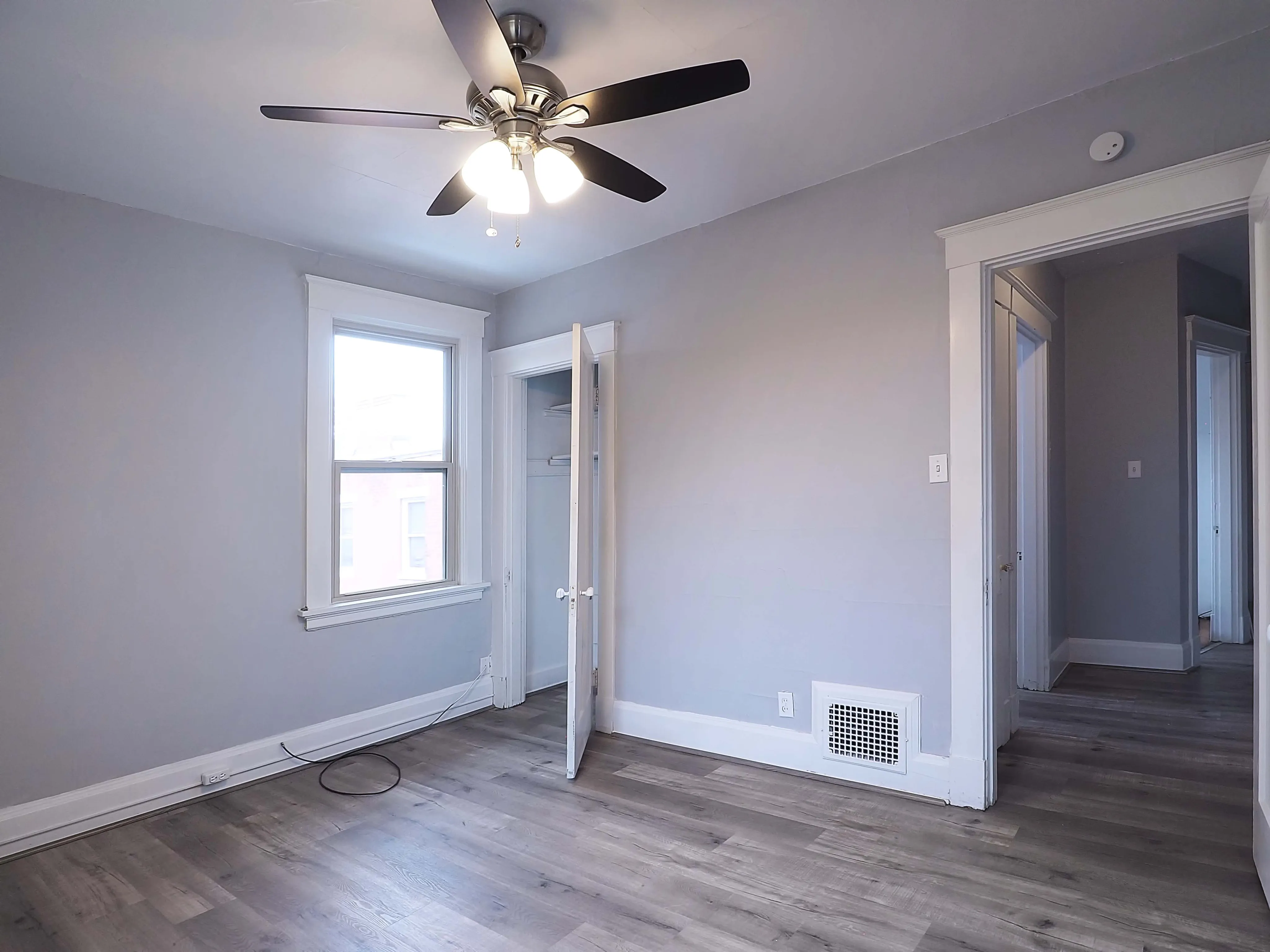 Bright, spacious room with natural light, modern ceiling fan, and sleek hardwood floors.