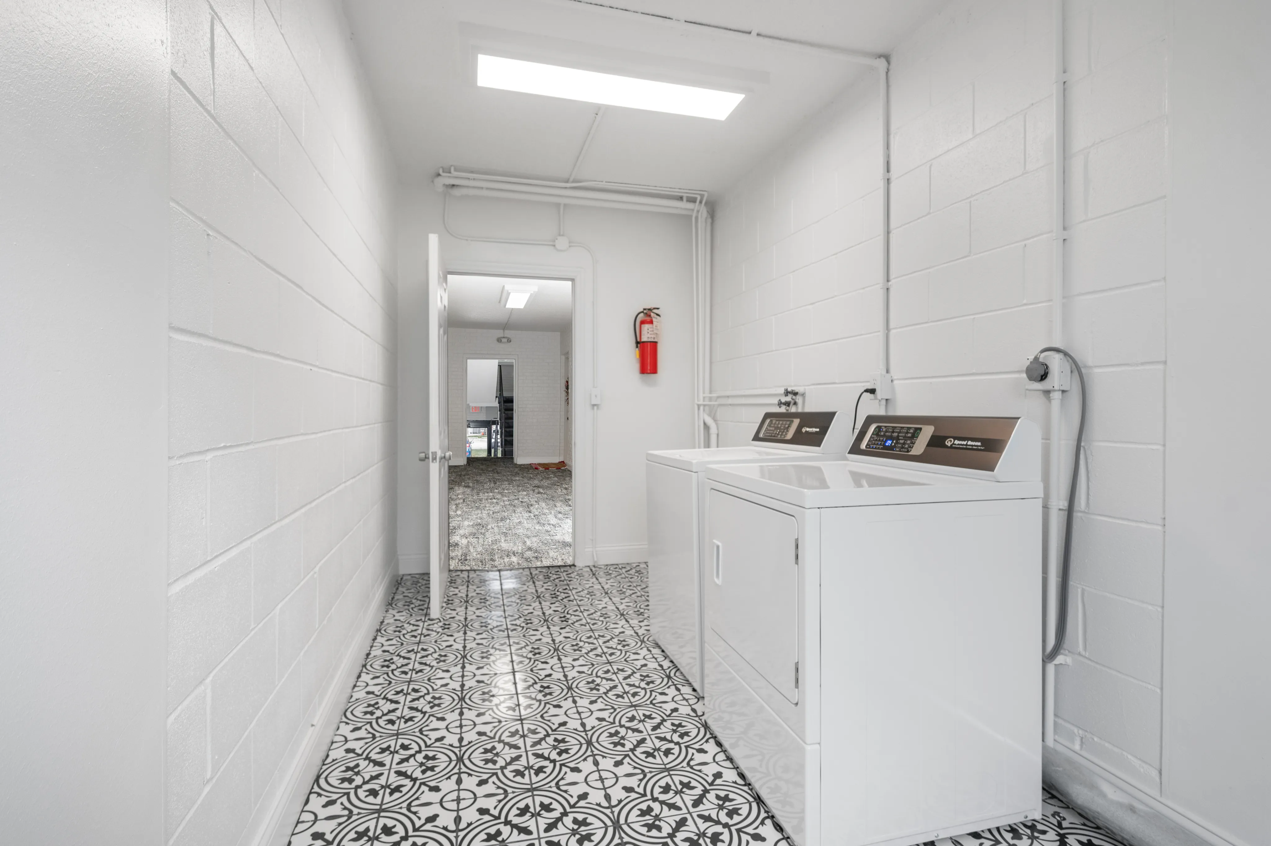 Modern laundry room with stylish patterned tile flooring and sleek white washer and dryer units.