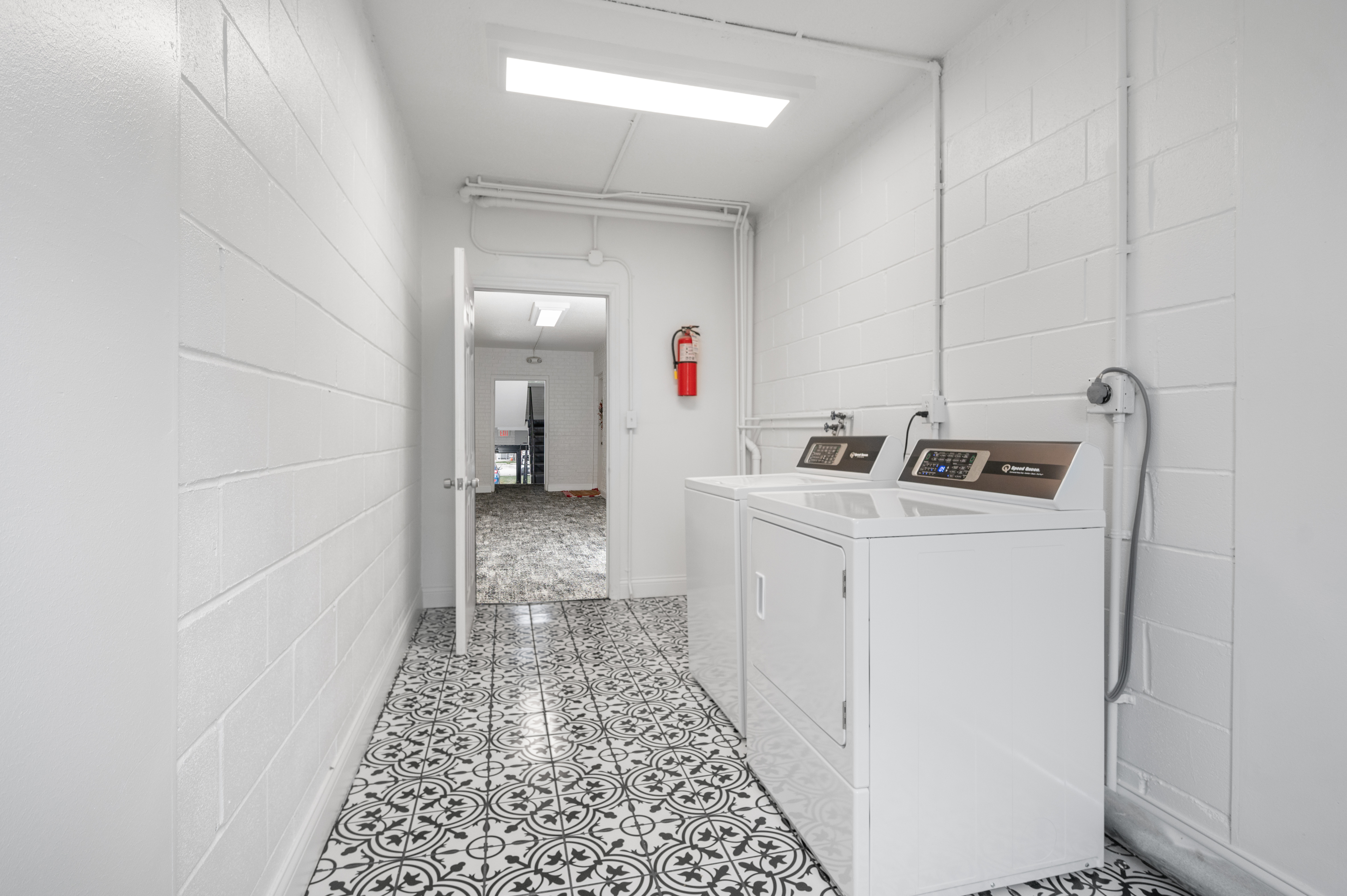 Modern laundry room with elegant patterned tile flooring and sleek appliances for convenient washing and drying.