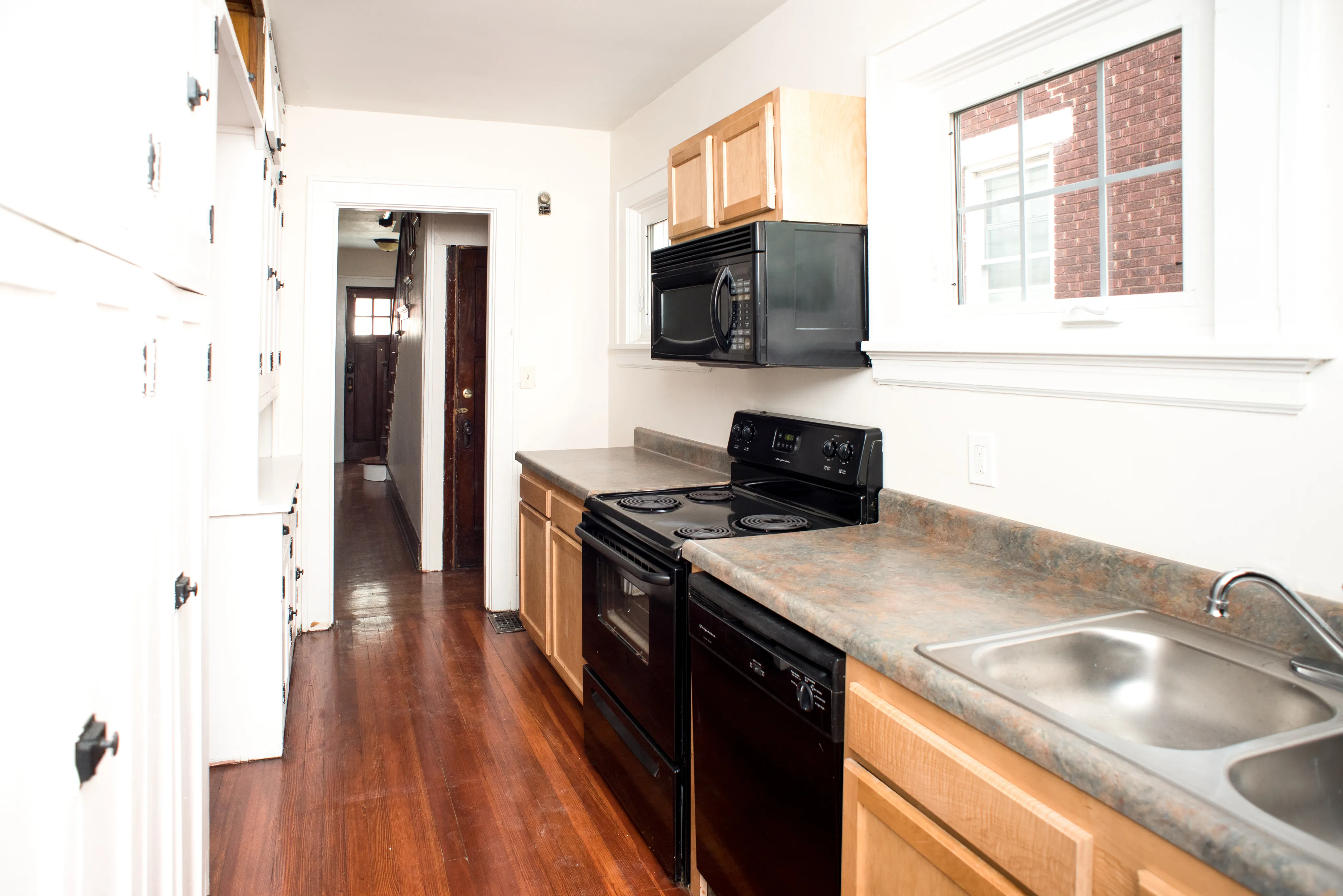 Bright and inviting kitchen with sleek countertops, modern black appliances, and white cabinetry, offering ample storage and natural light.