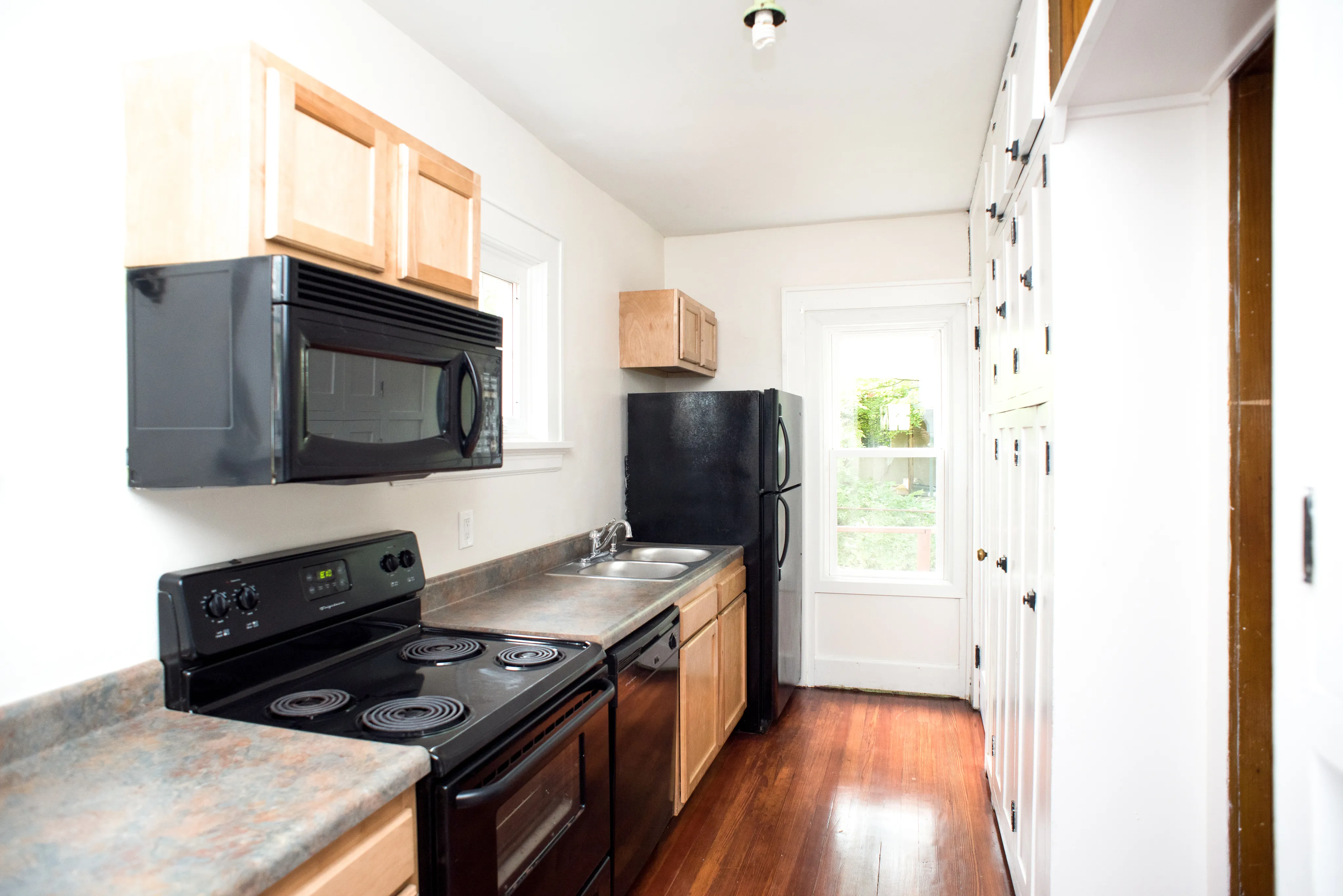 Bright and inviting galley kitchen with modern appliances, wood cabinetry, and a windowed view, highlighting functionality and style.