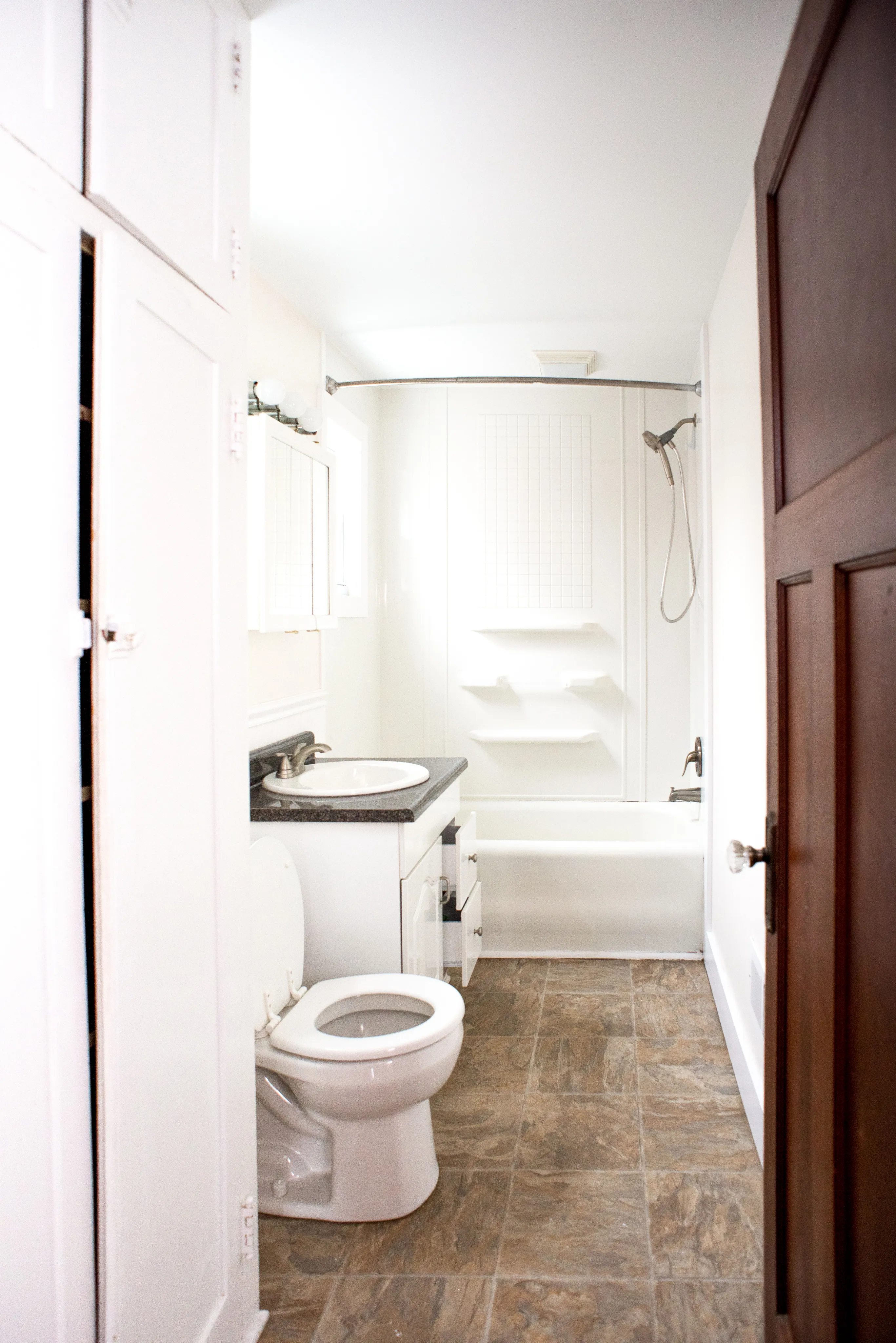 Bright and spacious bathroom featuring a modern design with a sleek bathtub, elegant tile flooring, and ample storage.
