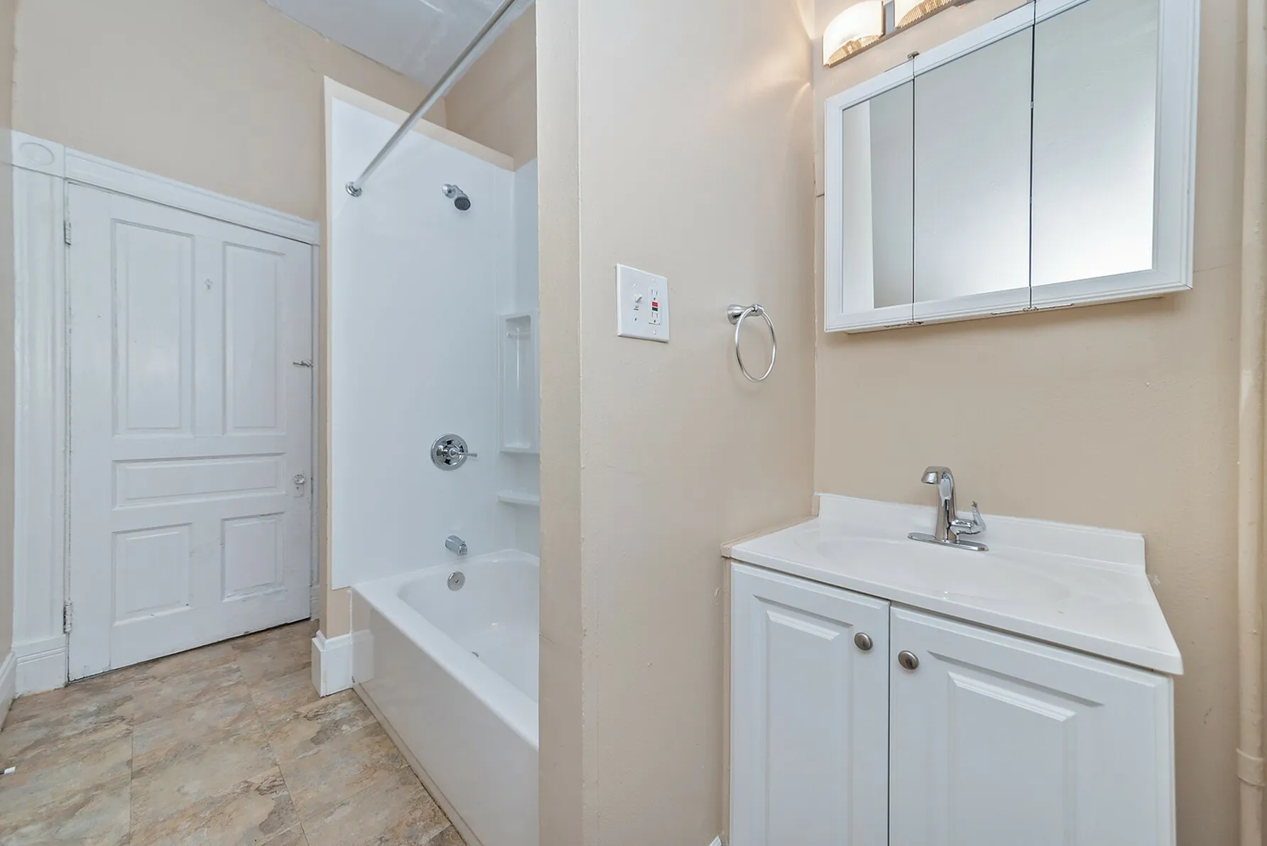 Modern bathroom featuring sleek white cabinetry, elegant sink, and pristine bathtub with shower.