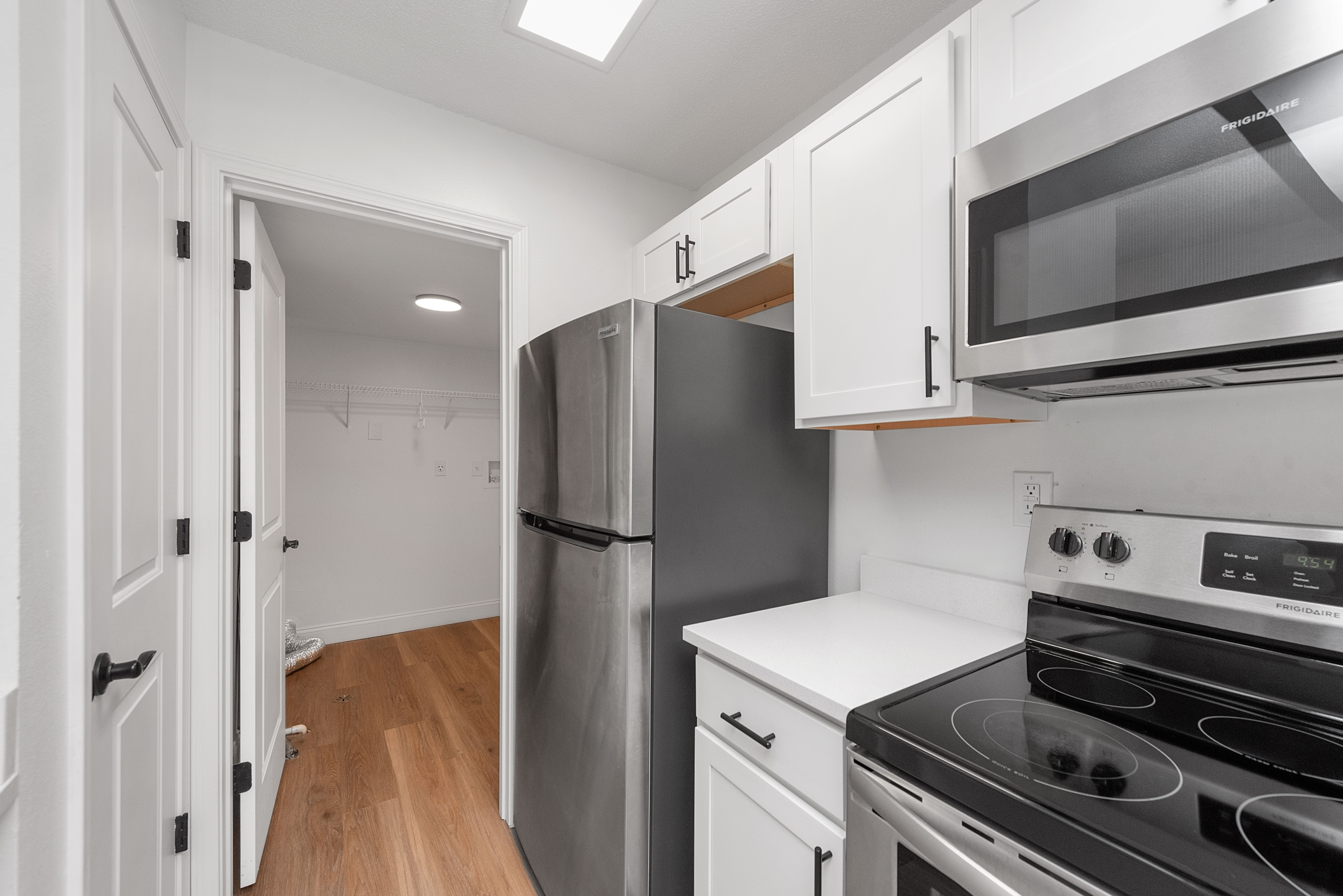 Sleek modern kitchen featuring stainless steel appliances, elegant white cabinetry, and warm wooden flooring.
