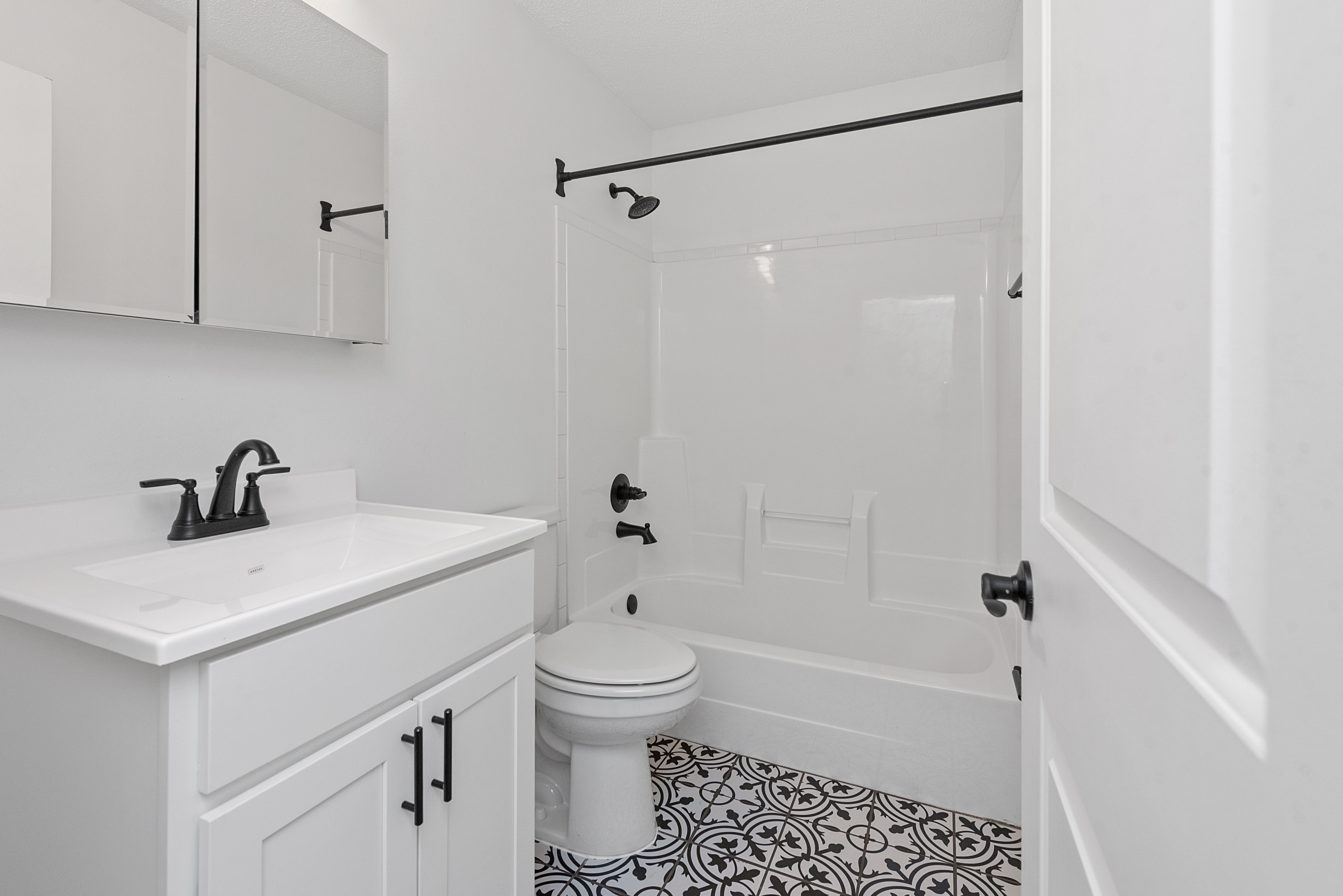 Modern bathroom featuring elegant black and white tiles, sleek fixtures, and a pristine white vanity for a stylish and refreshing ambiance.