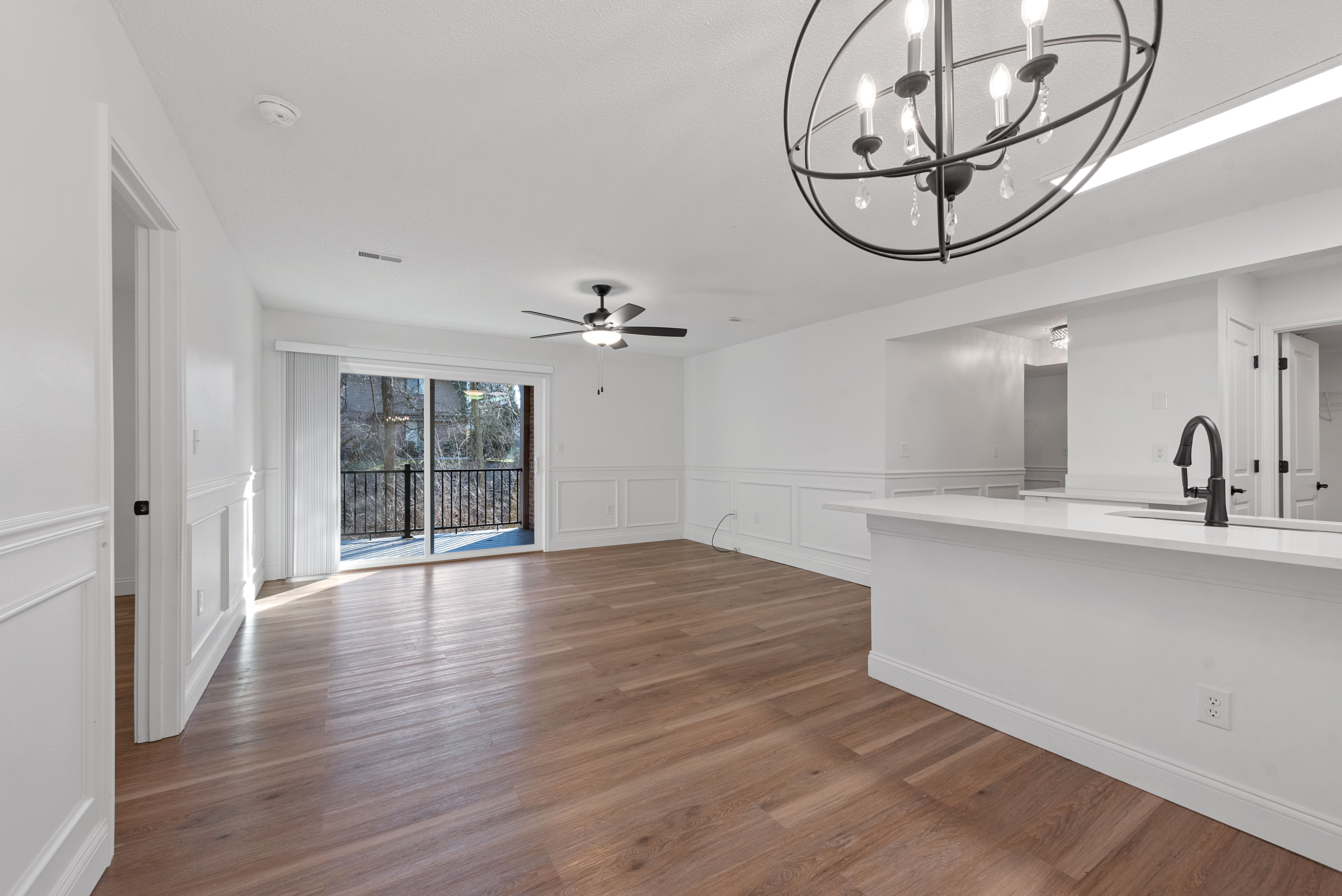 Spacious open-concept living area with elegant lighting, large sliding glass doors, and stylish hardwood flooring.