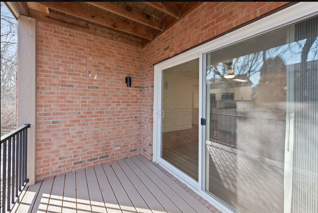 Charming brick patio with sliding glass doors leading to a cozy interior, perfect for relaxing and enjoying outdoor views.