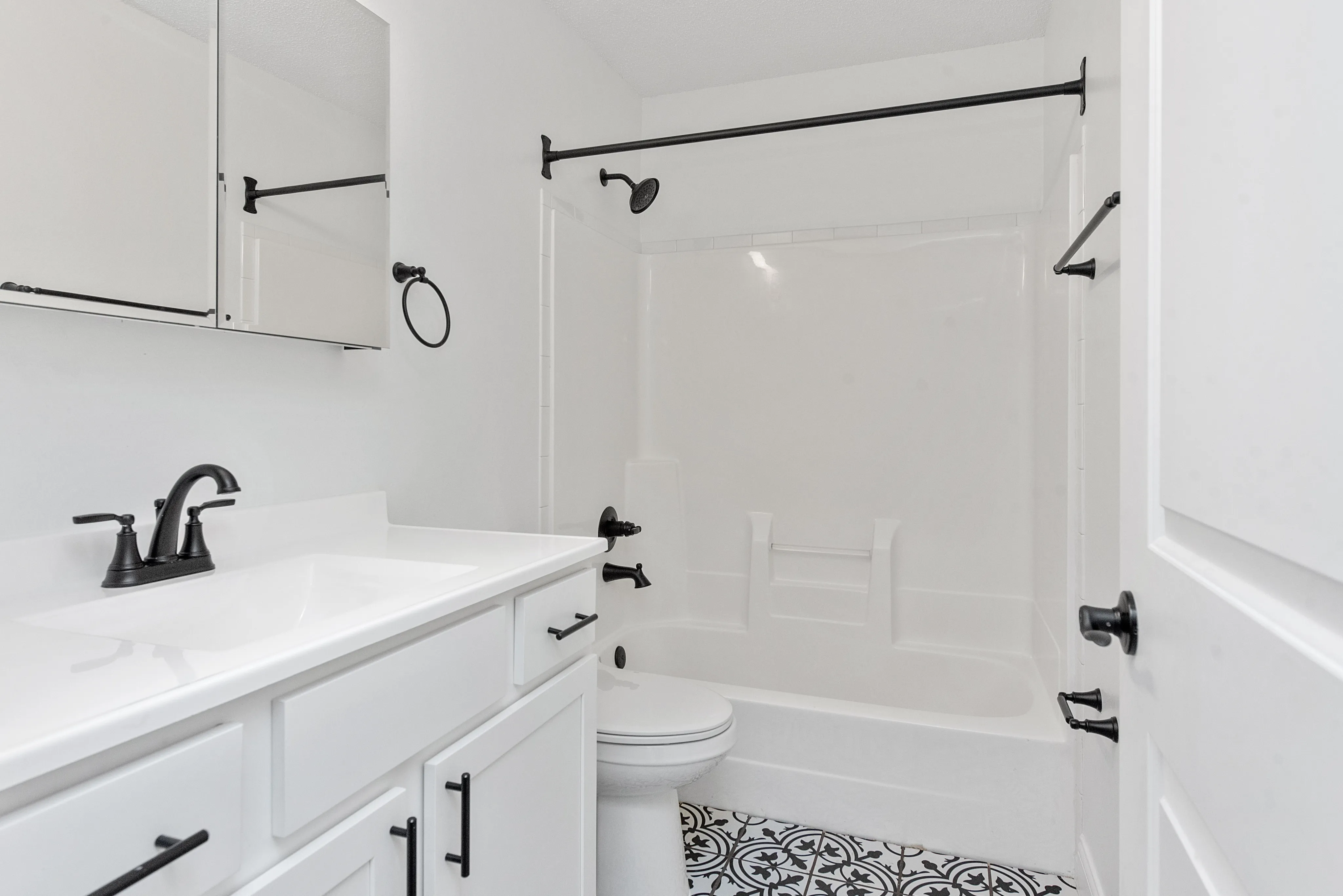 Elegant bathroom featuring chic black fixtures, a spacious vanity with modern cabinetry, and stylish patterned floor tiles.