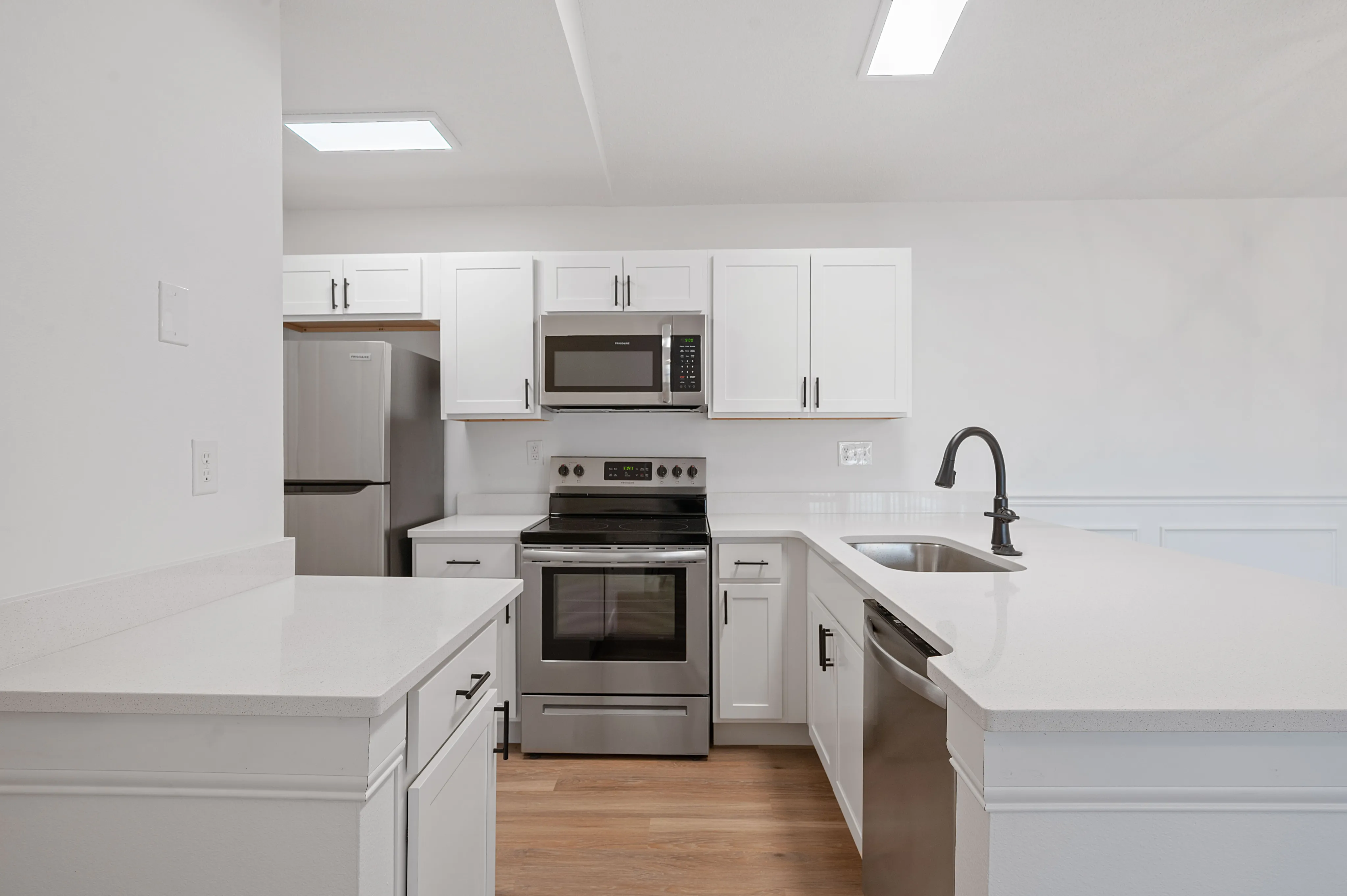 Modern kitchen with sleek white cabinetry, stainless steel appliances, and a spacious quartz countertop island.