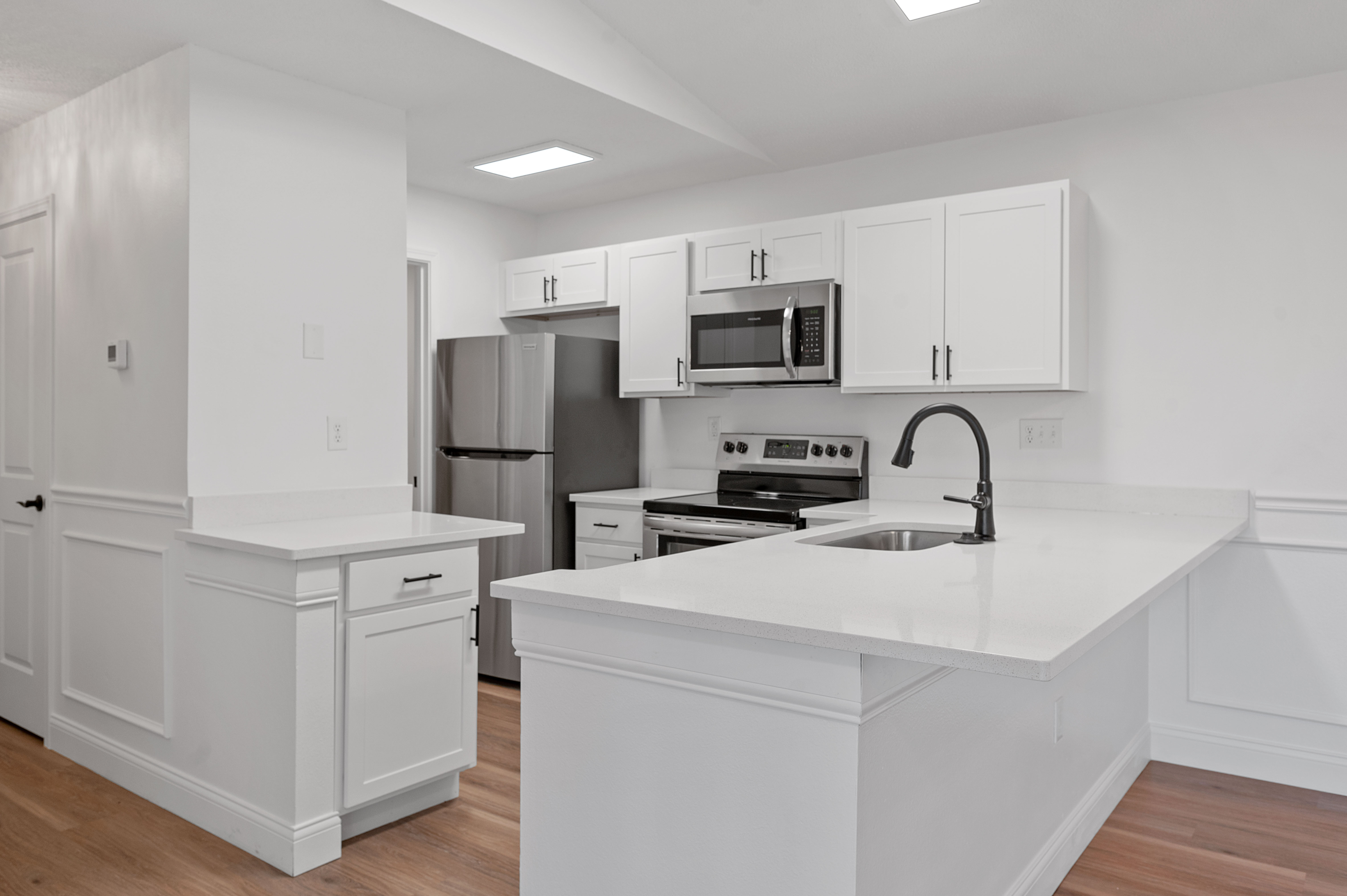 Modern kitchen with sleek white cabinetry, stainless steel appliances, and elegant quartz countertops.
