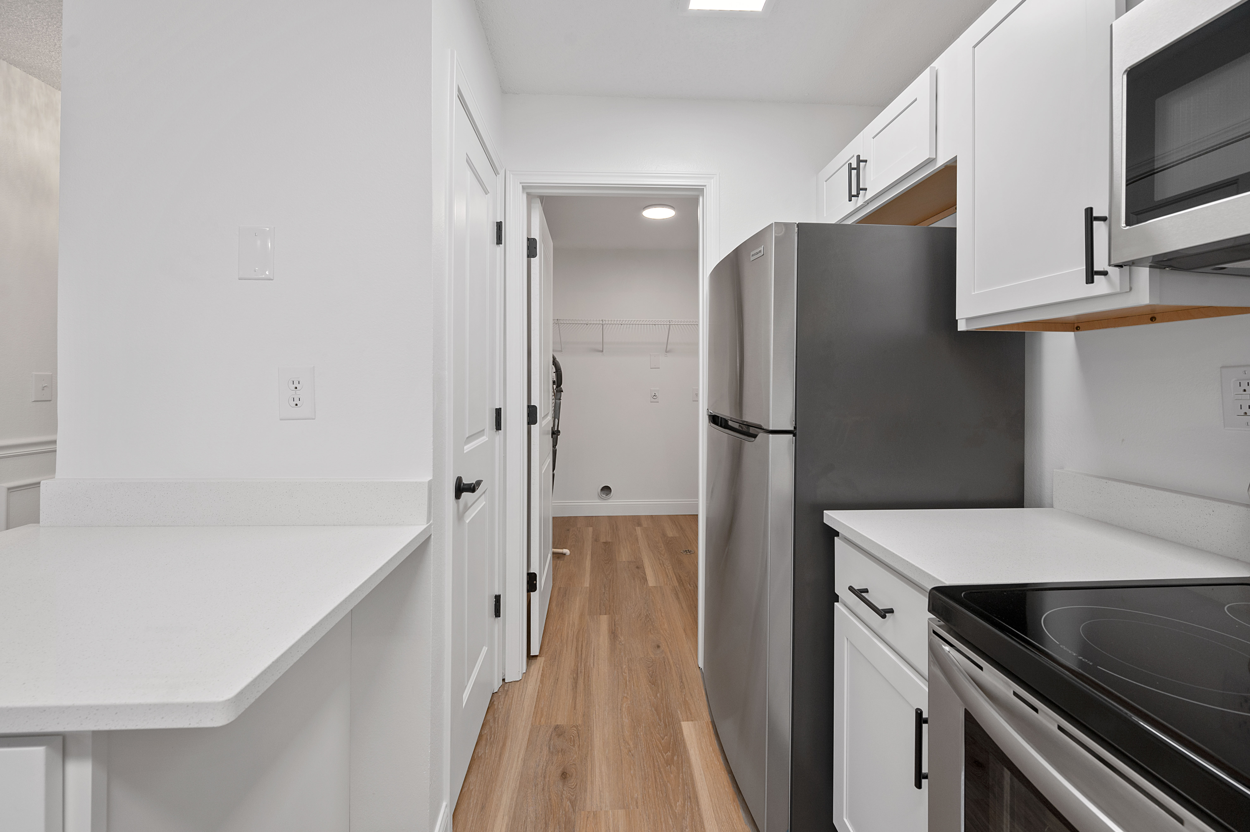 Modern kitchen with sleek stainless steel appliances, elegant white cabinetry, and warm wood flooring.