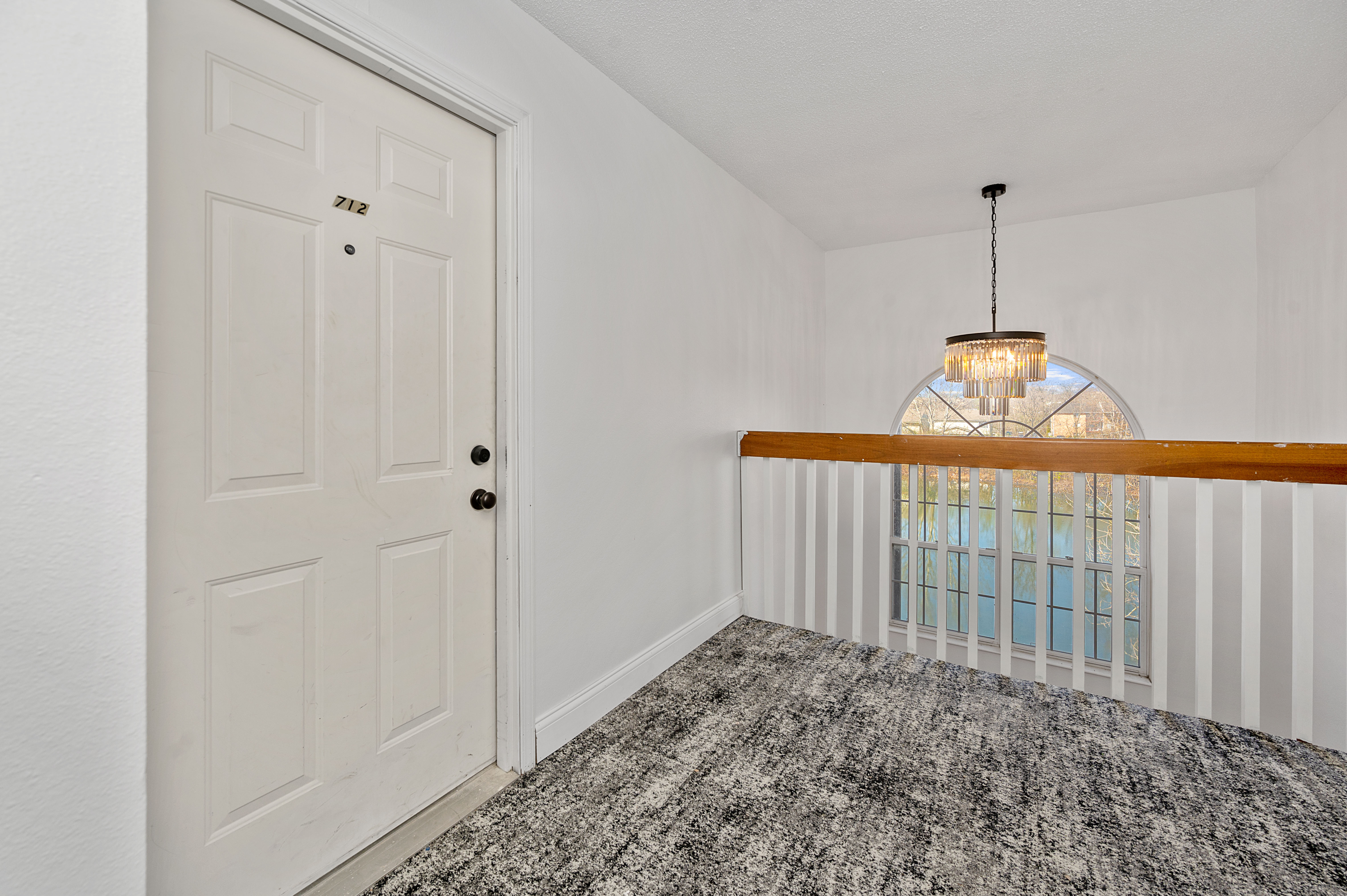 Inviting hallway with elegant lighting and a bright arched window view, creating a warm and welcoming atmosphere.