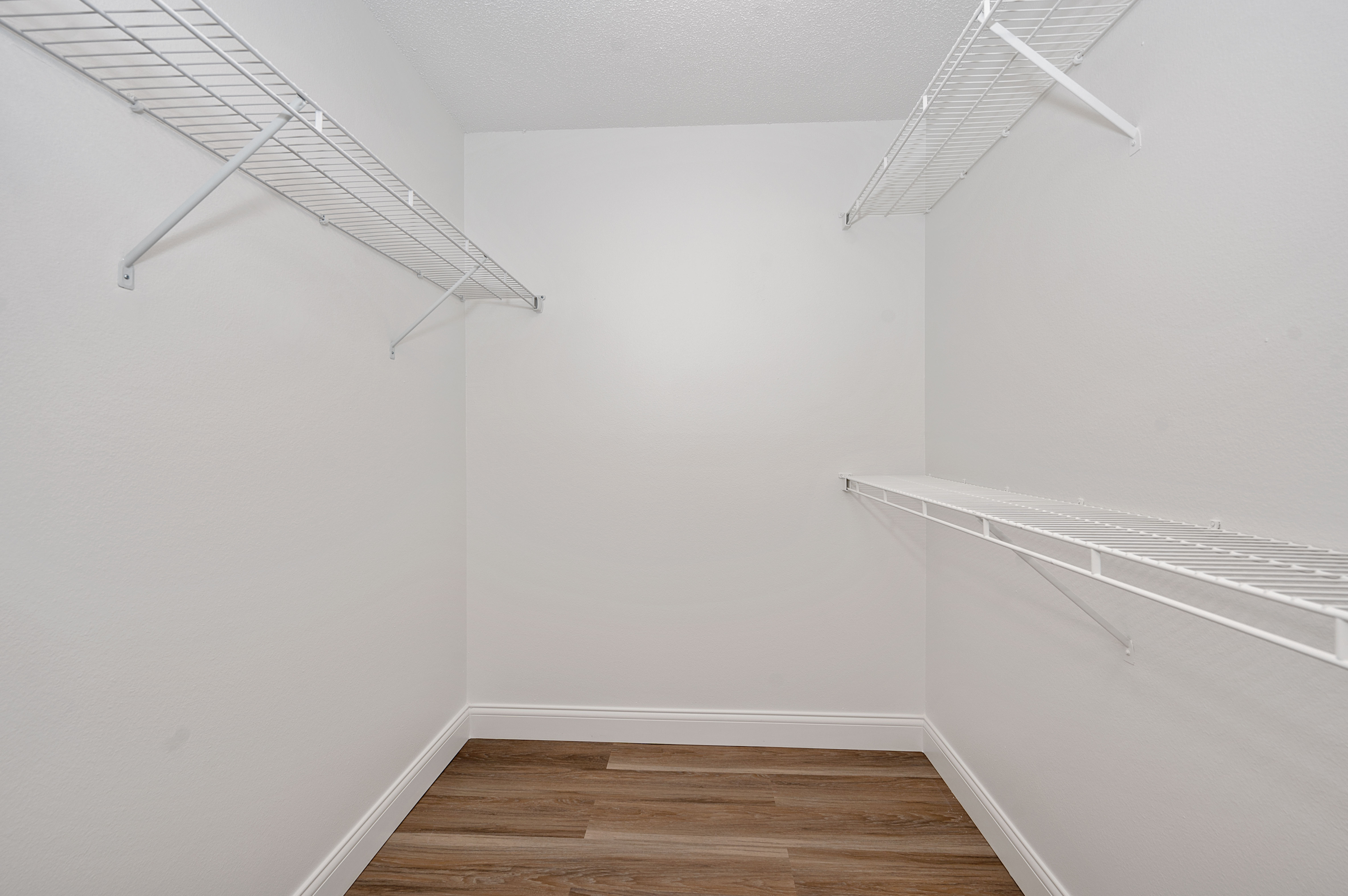 Spacious walk-in closet with hardwood floors and ample shelving space, perfect for organized storage.