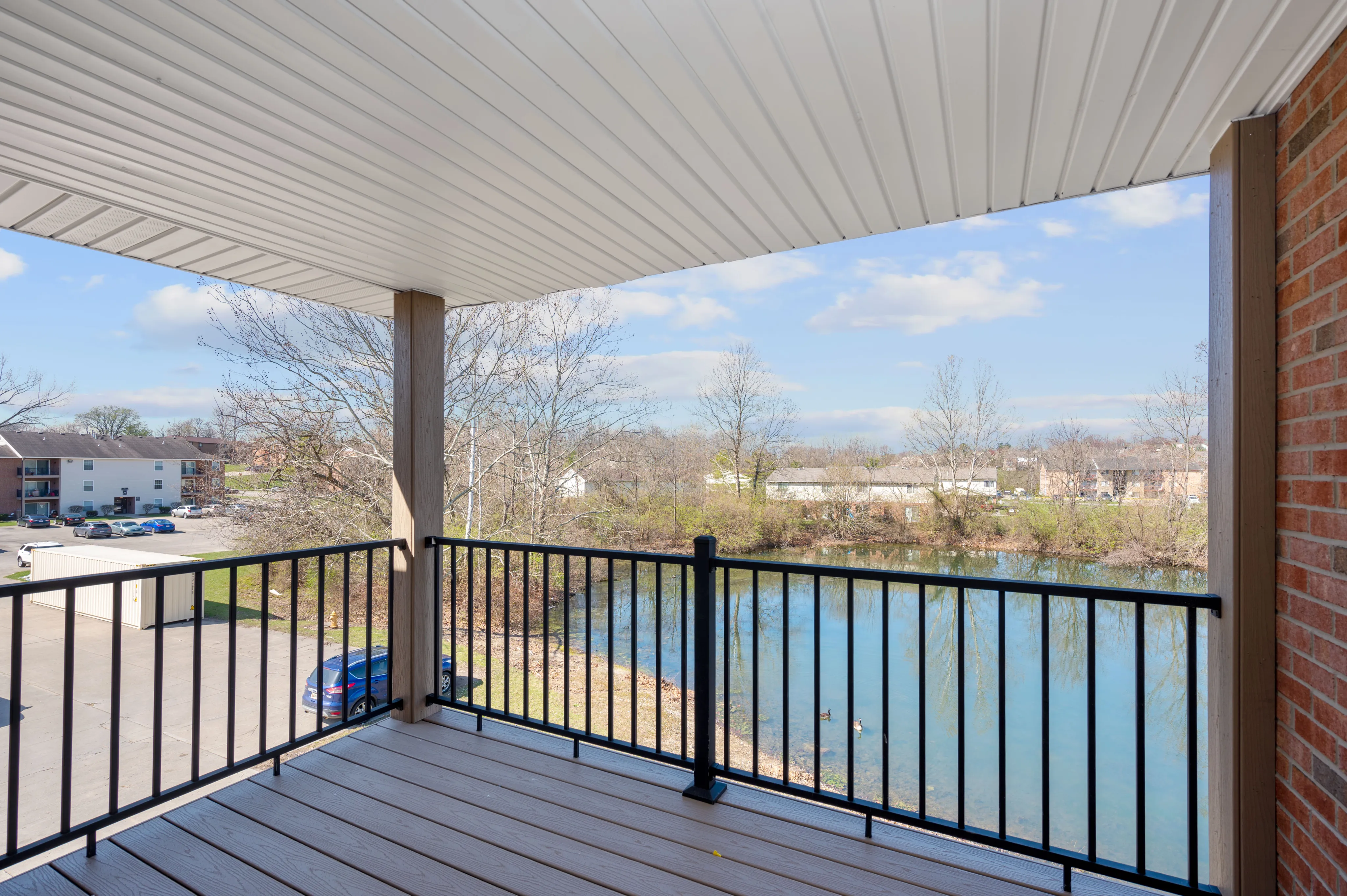 Charming apartment balcony with a serene pond view, featuring modern railing and spacious layout.