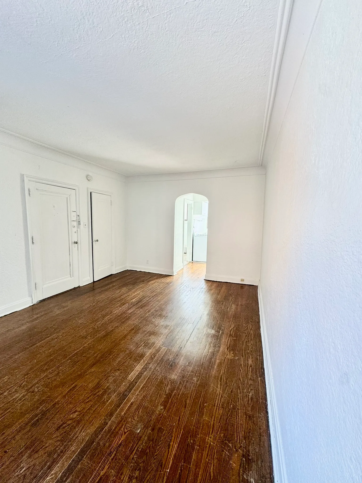 Spacious and bright room with elegant wooden flooring and neutral walls, perfect for personalized styling.