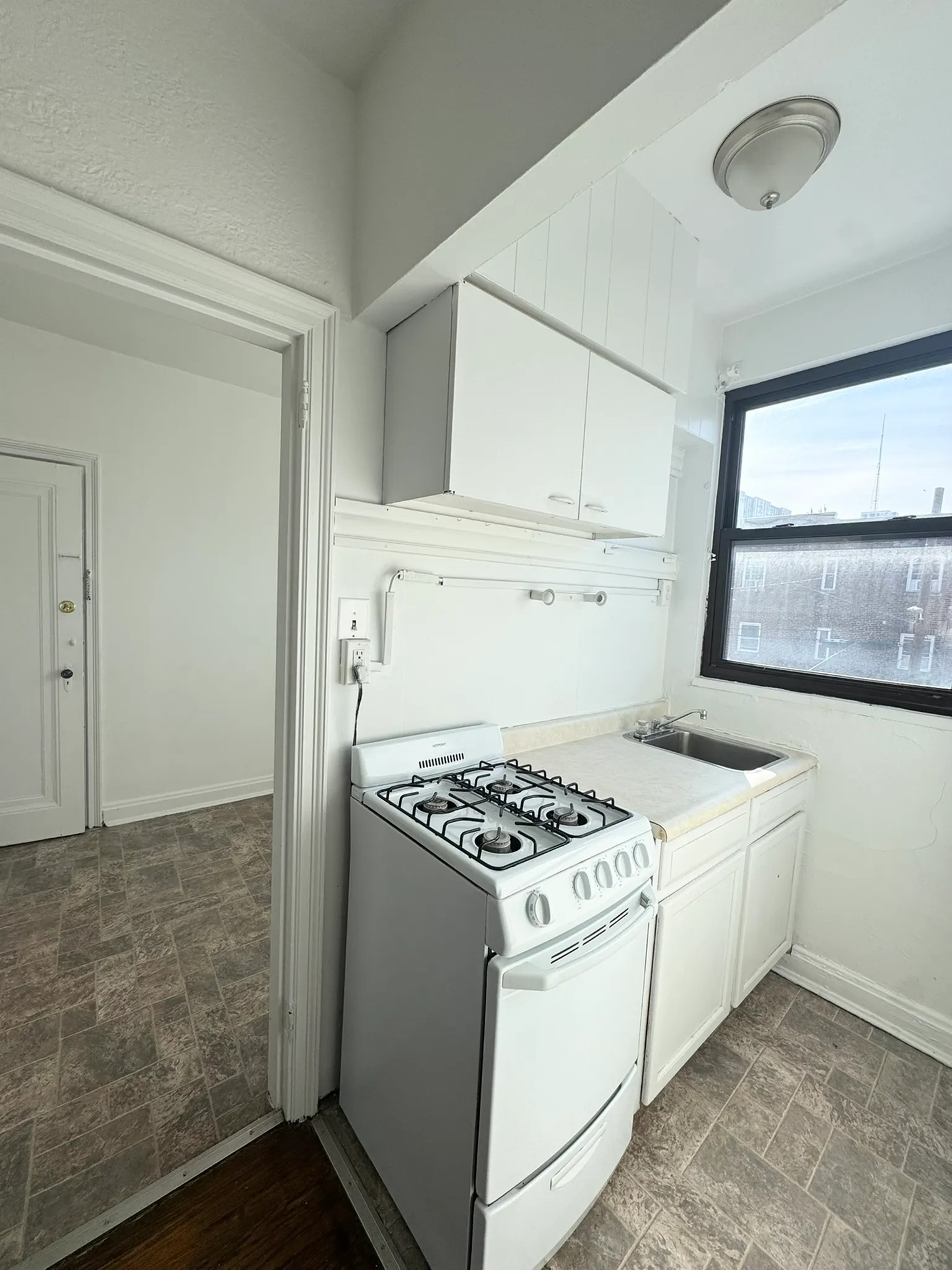 Charming kitchen with a classic white stove, ample cabinetry, and a bright window offering a warm and inviting atmosphere.