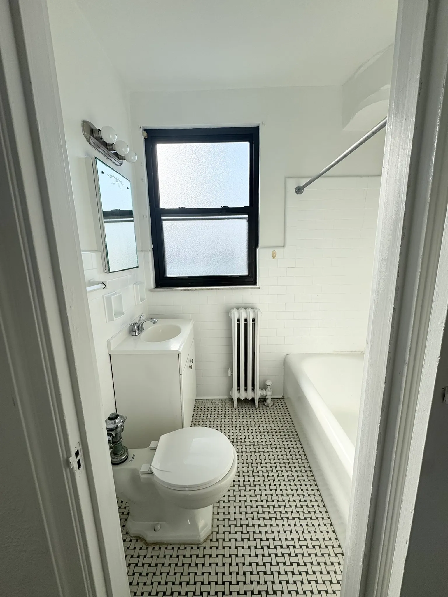 Bright and modern bathroom featuring elegant tile flooring, pristine white fixtures, and a large window for natural light.