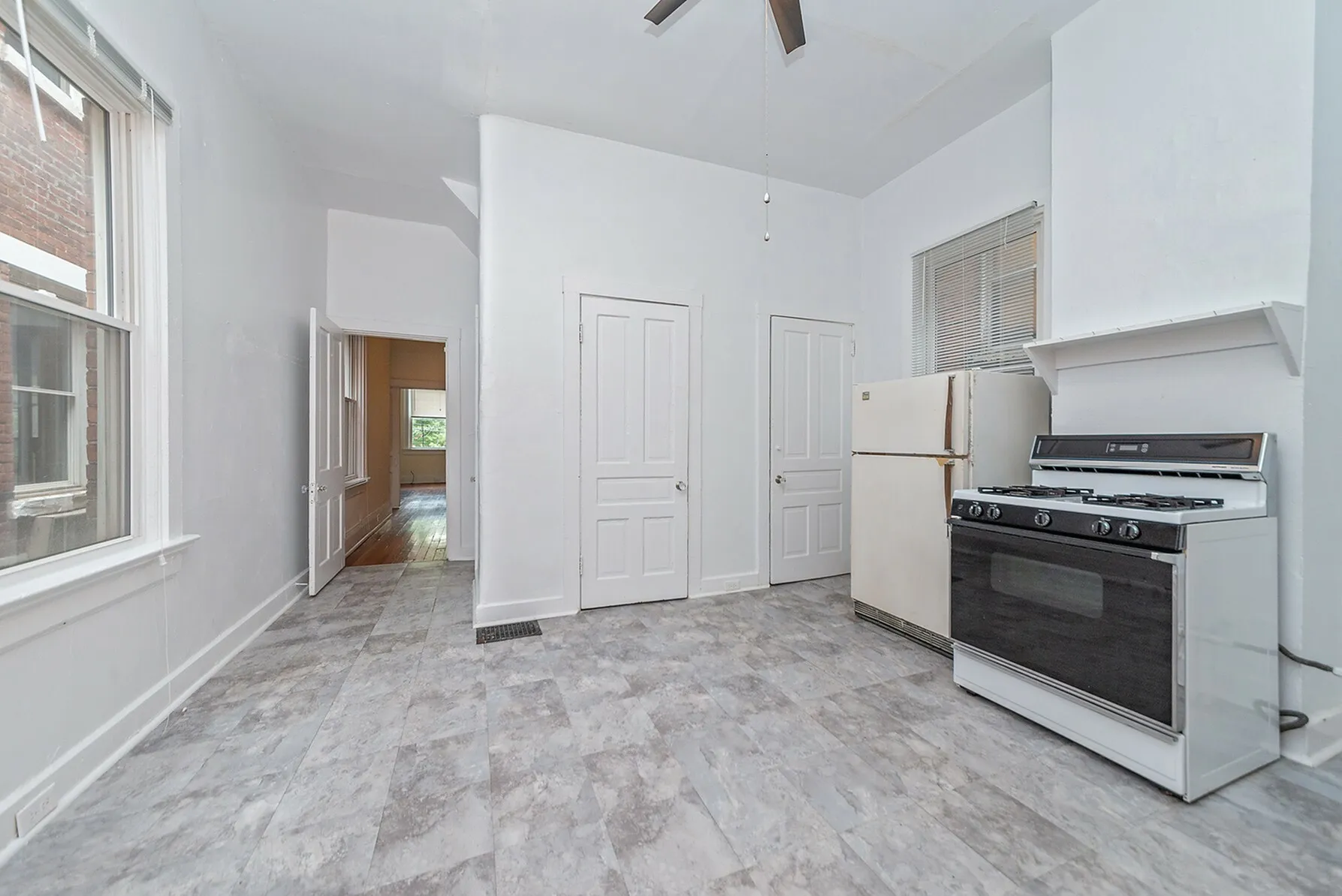 Bright kitchen with modern appliances, large windows, and sleek tile flooring, offering a spacious and airy feel.