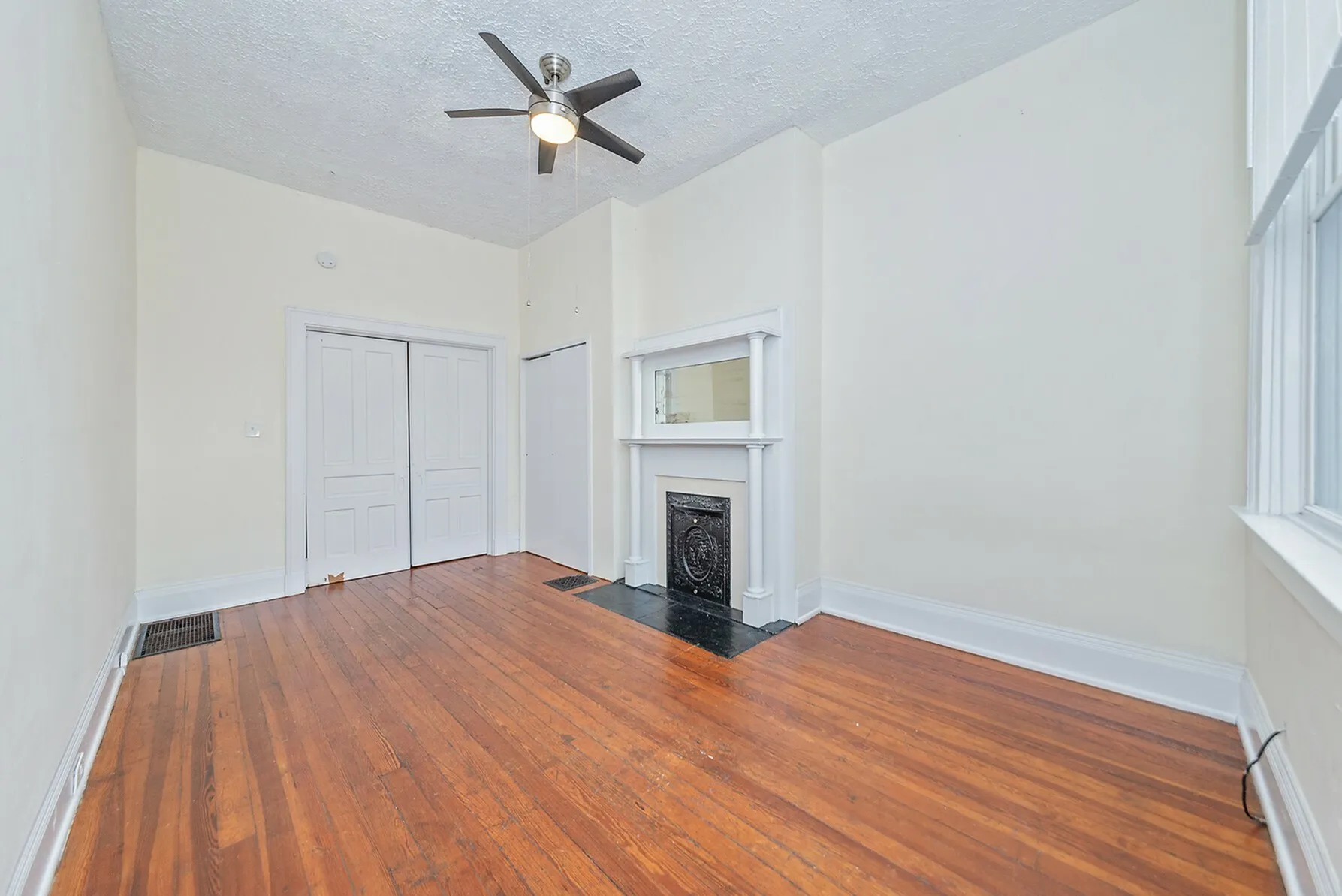 Charming living room featuring beautiful hardwood floors, a decorative fireplace, and a modern ceiling fan.