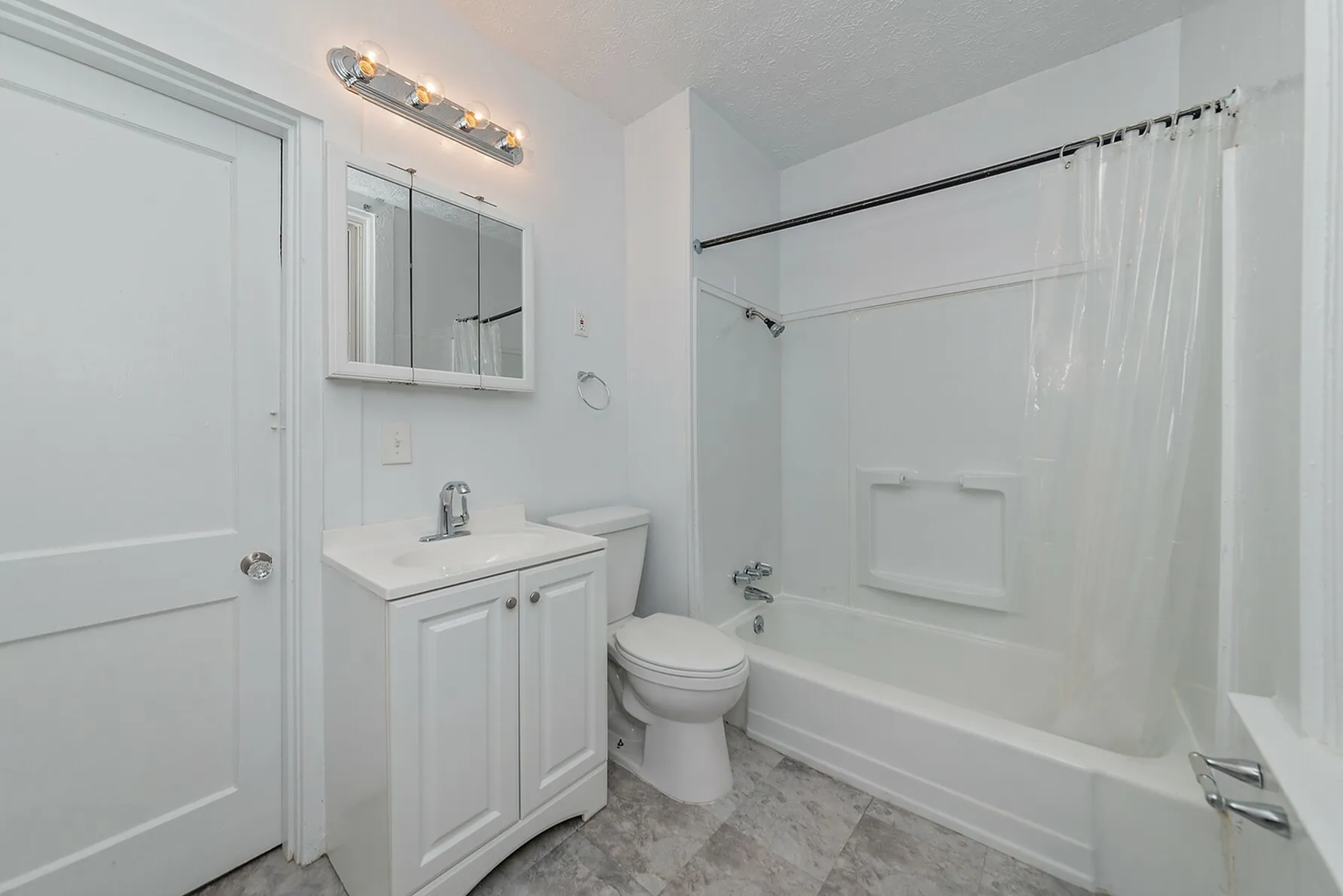 Bright and modern bathroom featuring a sleek vanity, accessible shower-bath combo, and elegant lighting.