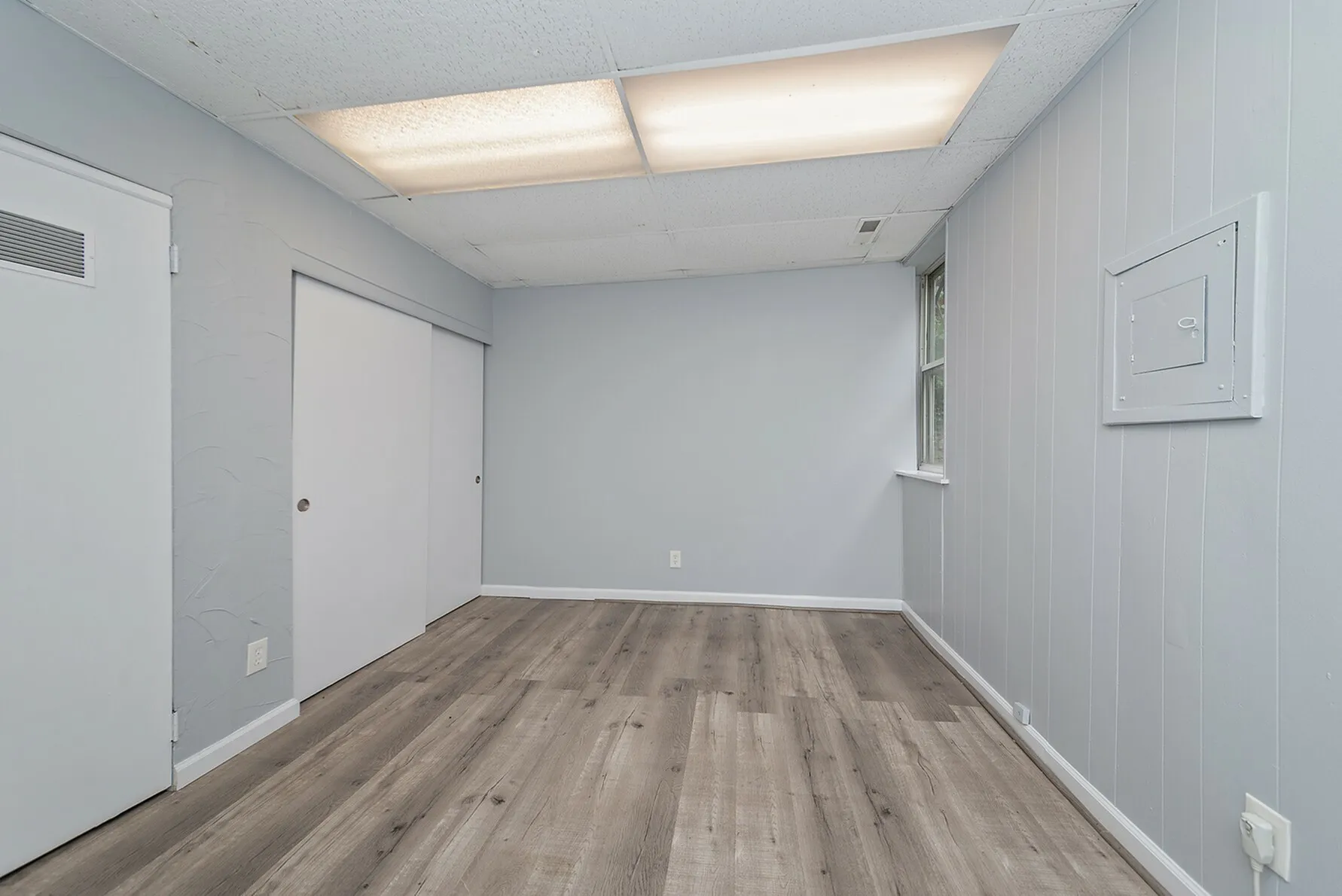 Bright, freshly remodeled room with elegant wood flooring and soft gray walls, perfect for a cozy living space.
