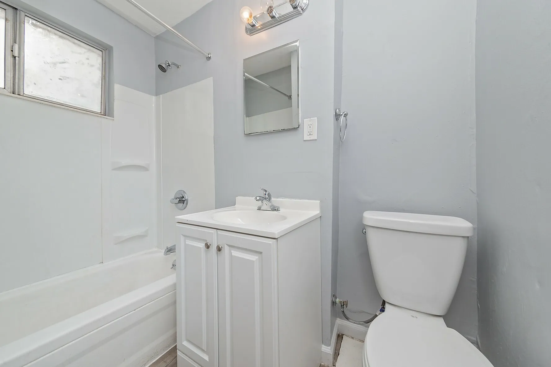 Modern bathroom with sleek fixtures, a clean white bathtub, and a contemporary vanity set against a stylish gray wall.