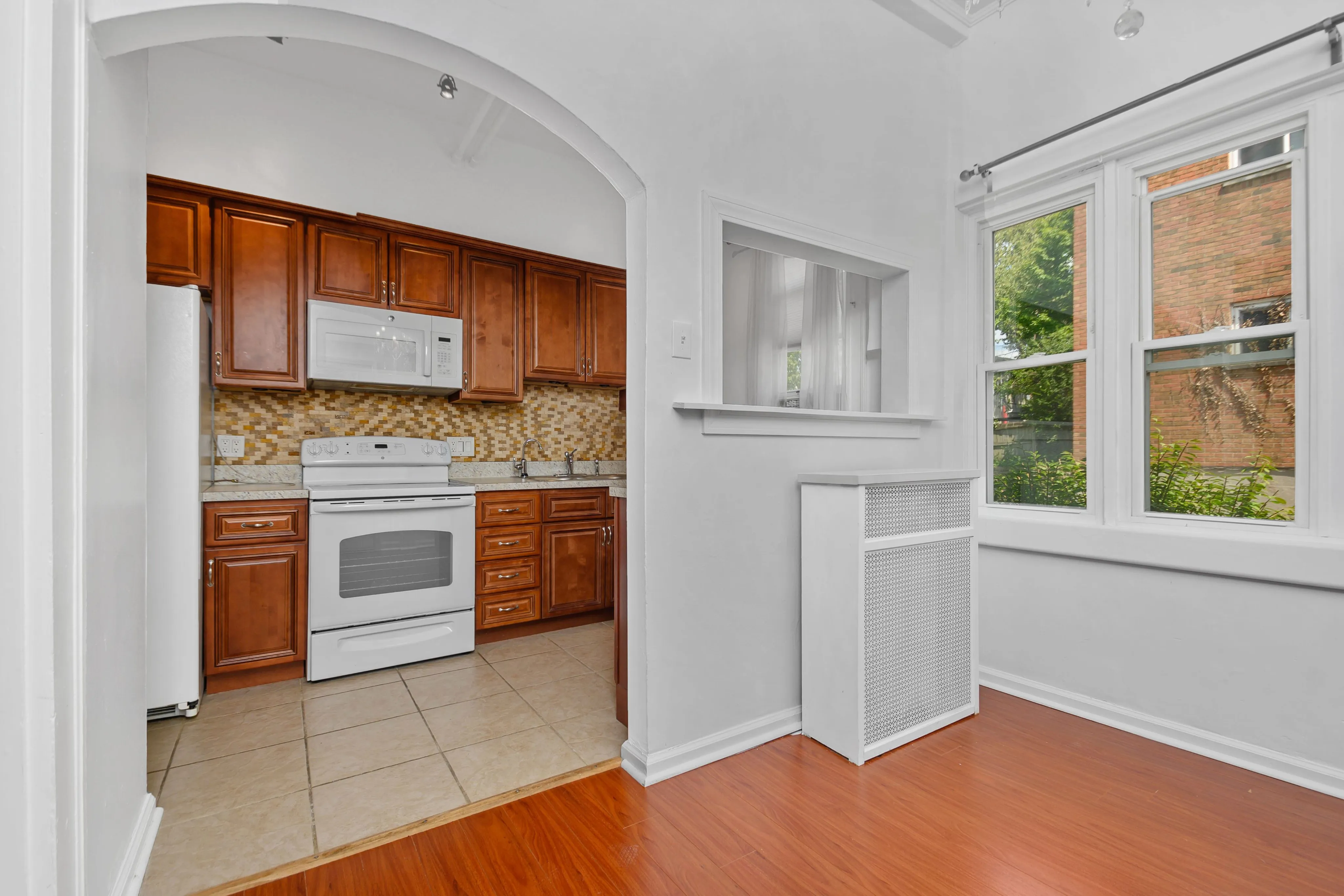 Charming kitchen with rich wood cabinets, modern appliances, and bright natural light through large windows.