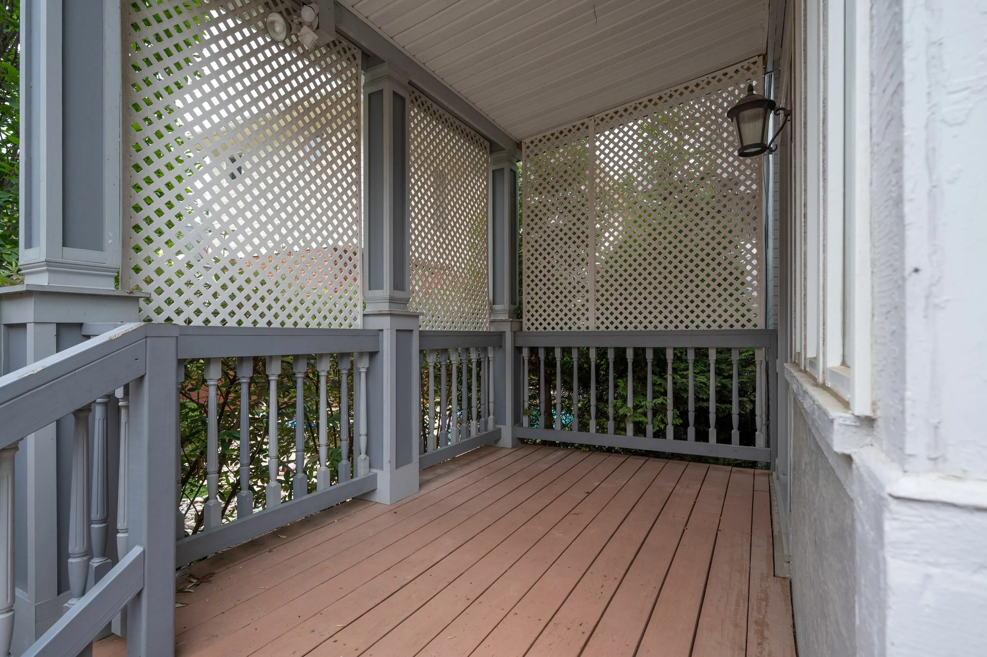Charming screened porch with decorative lattice, inviting natural light and garden views.
