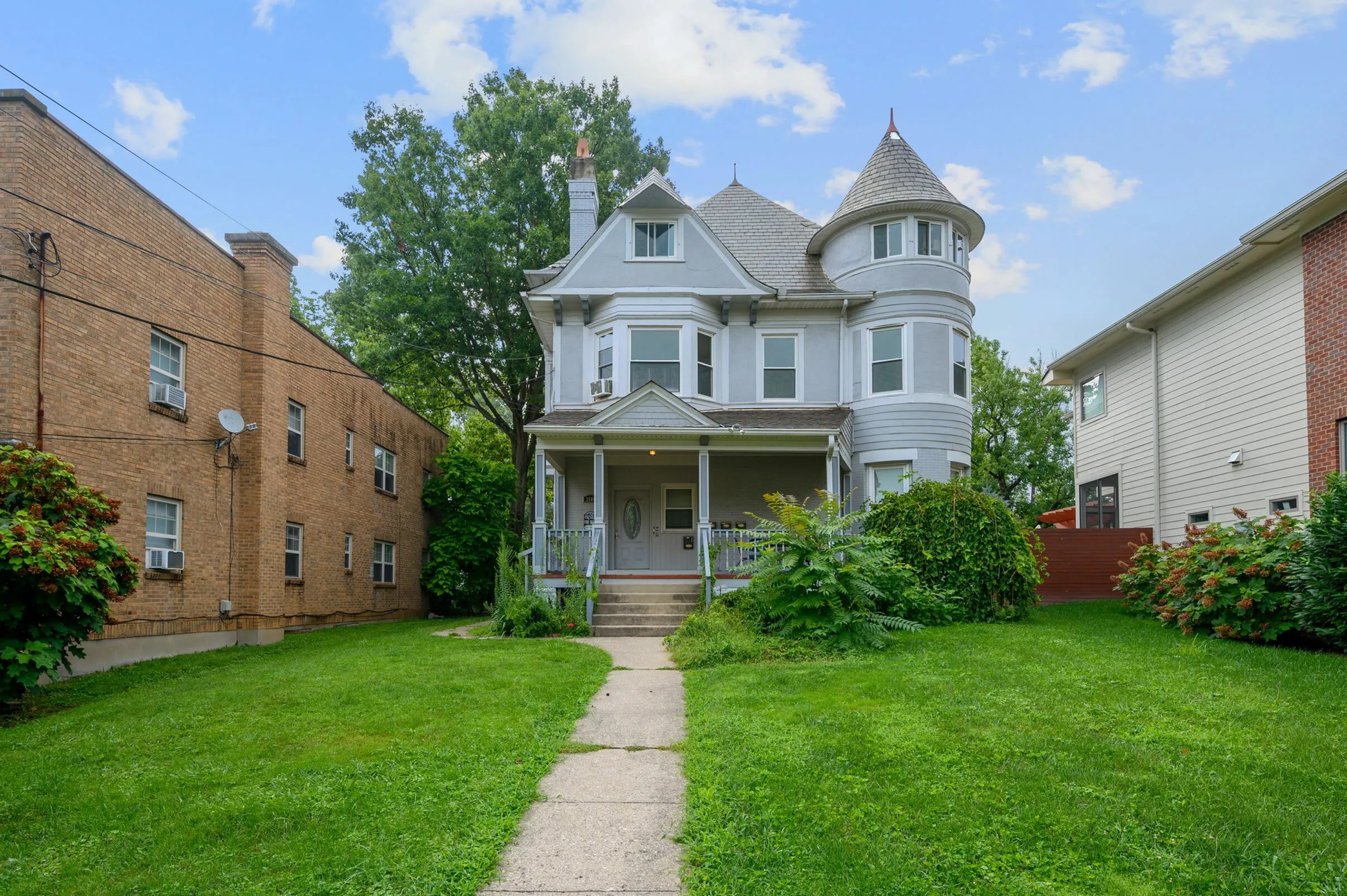 Charming Victorian-style house with elegant turret, inviting front porch, and lush green lawn, perfect for family living.