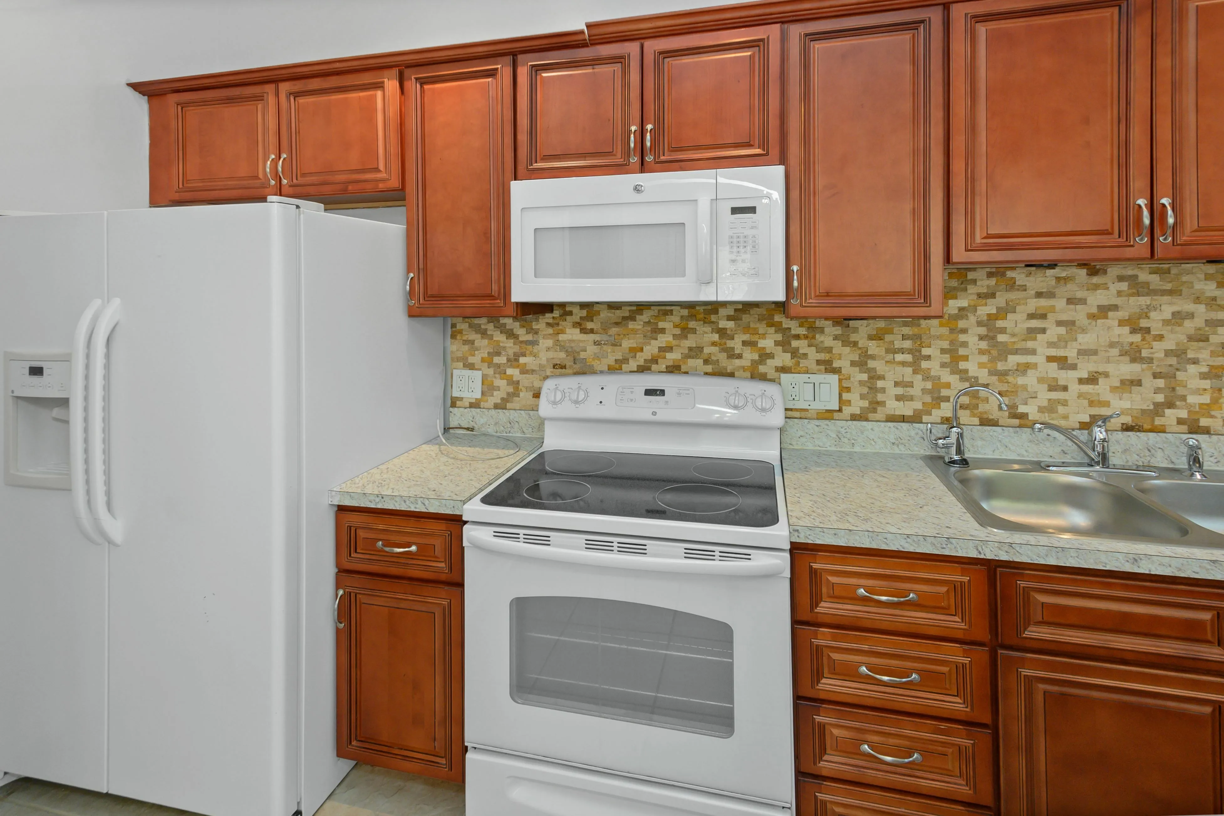 Modern kitchen with elegant wooden cabinets, sleek white appliances, and stylish mosaic backsplash.